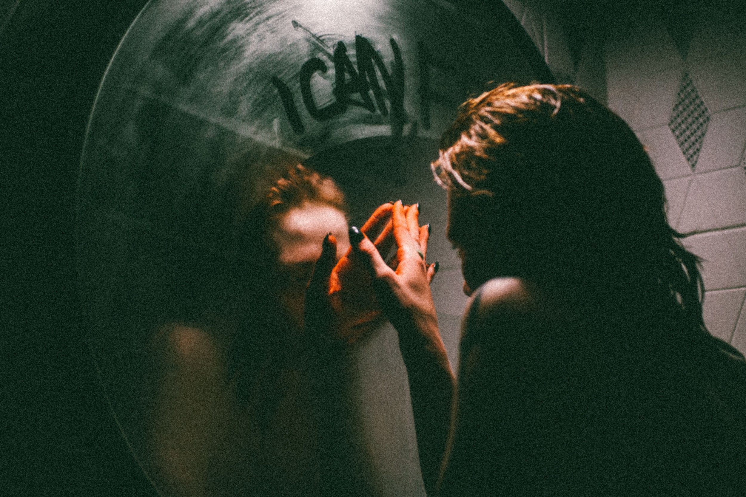 Девушка рисует на запотевшем круглом зеркале буквы