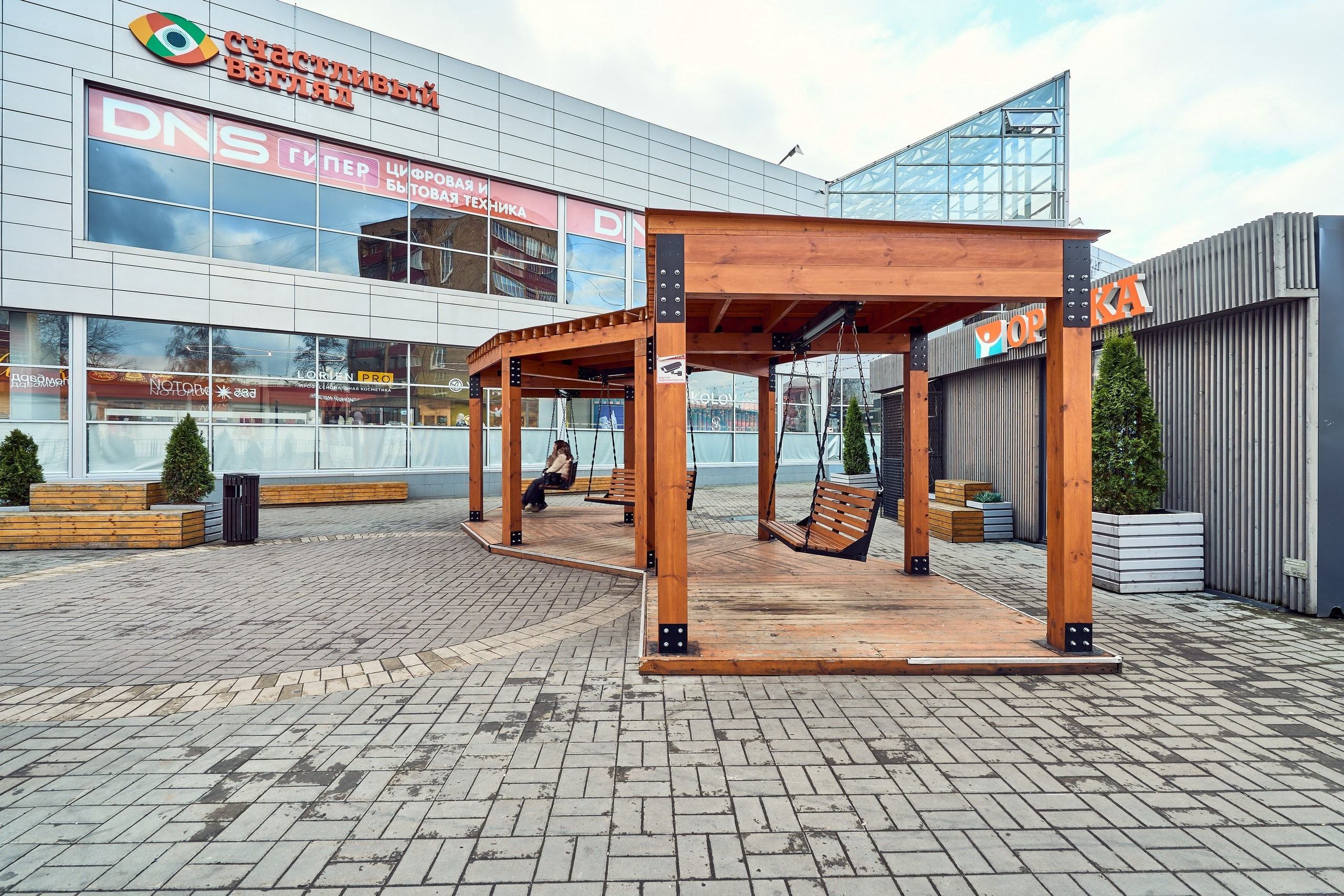 Архитектурная съемка ТЦ "Солнечный" в г. Раменское с вечно модными и актуальными качелями на переднем плане и геометрией главного здания ТЦ на заднем