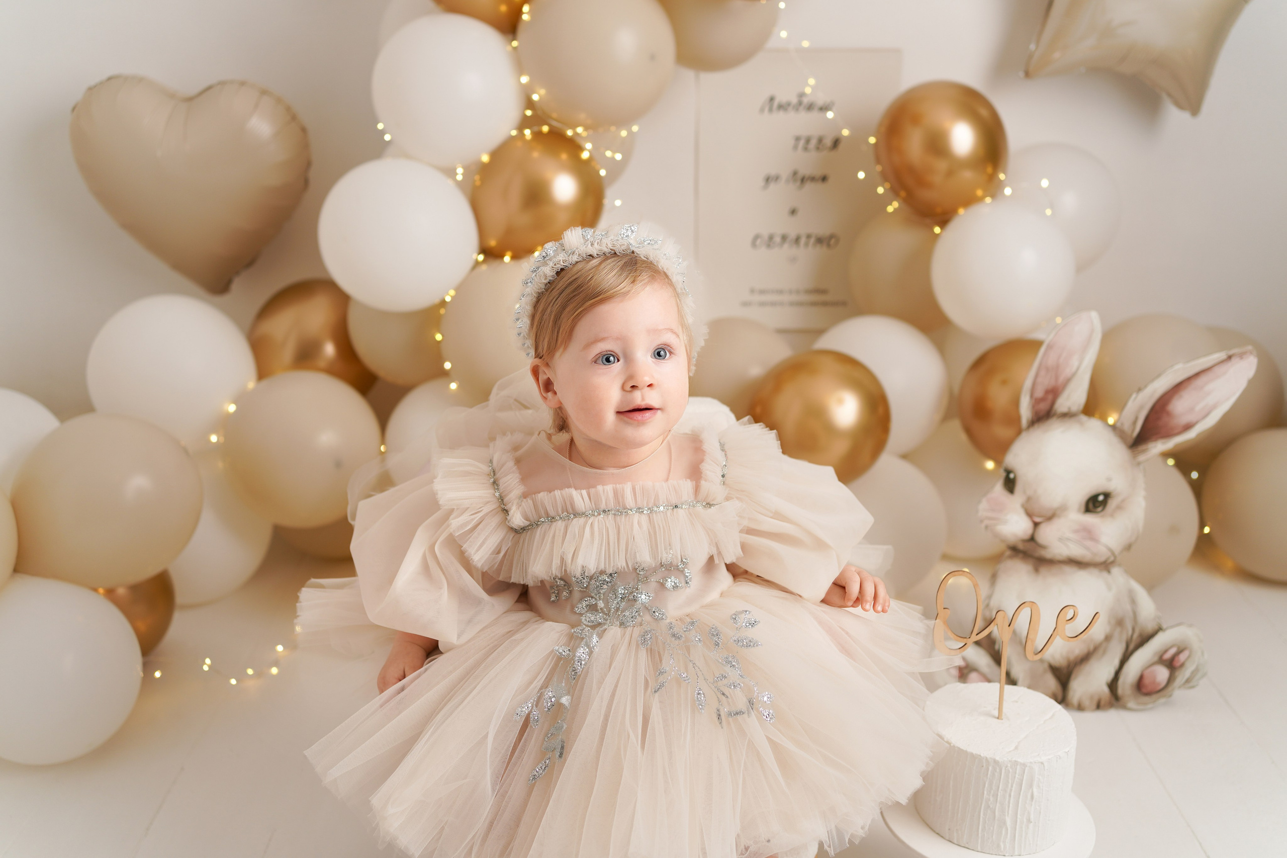 Детский фотограф Оксана Иваний. На фото малышка в пышном бежевом платье на фоне воздушных шариков.