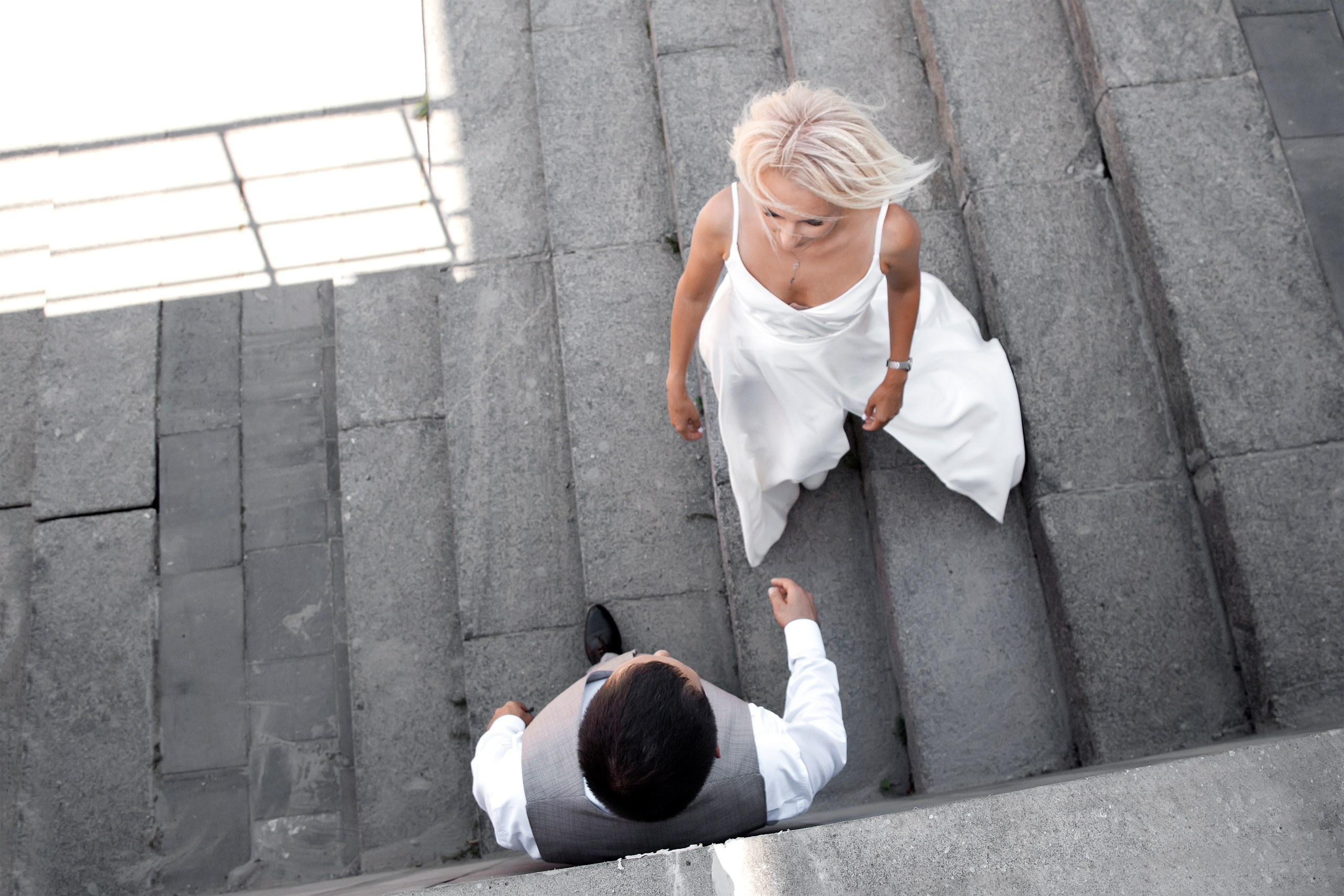 Невеста подходит к жениху на серой лестнице в тени, свадебная съёмка в Ульяновске