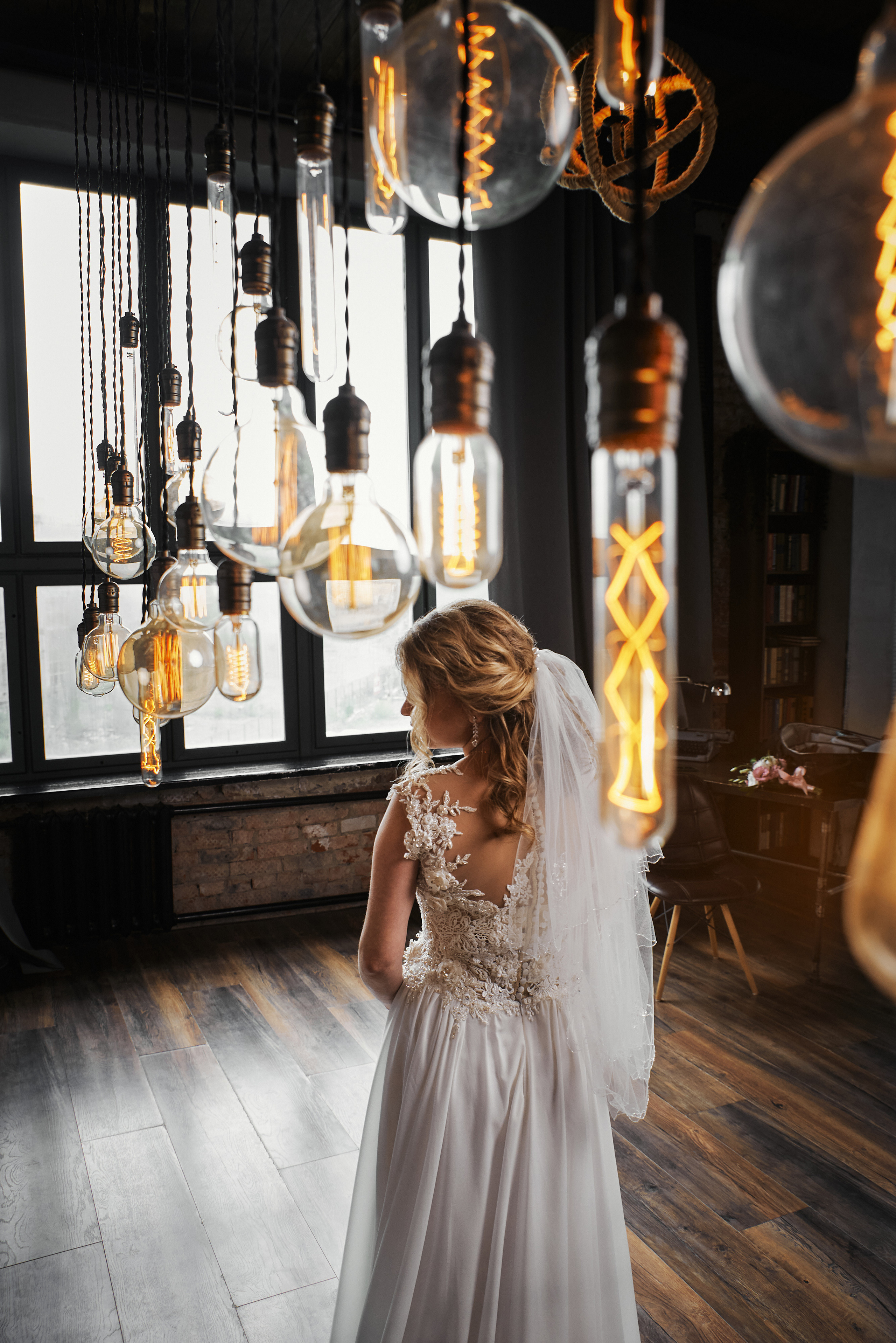 Невеста стоит на фоне красивых лампочек в фотостудии Томсон