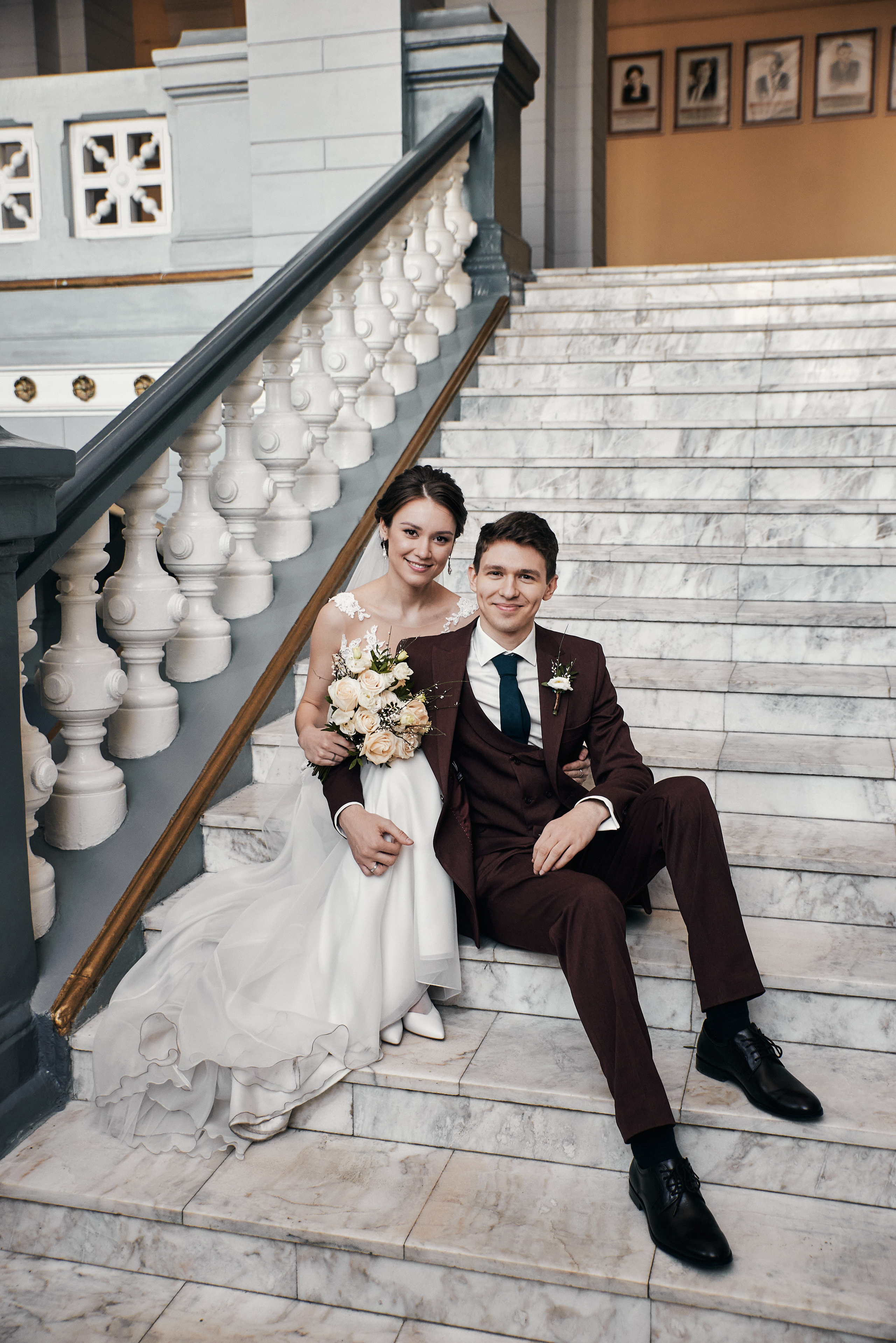 Молодожены сидят и смеются на лестнице в Томском политехническом университете