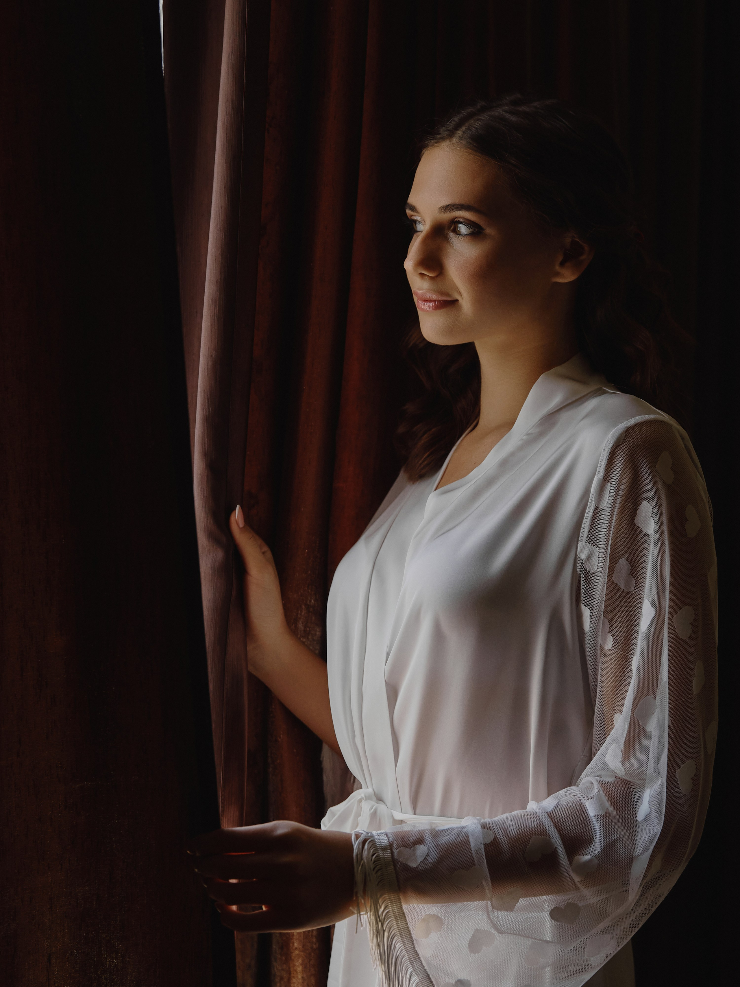 Невеста смотрит в окно на темном фоне