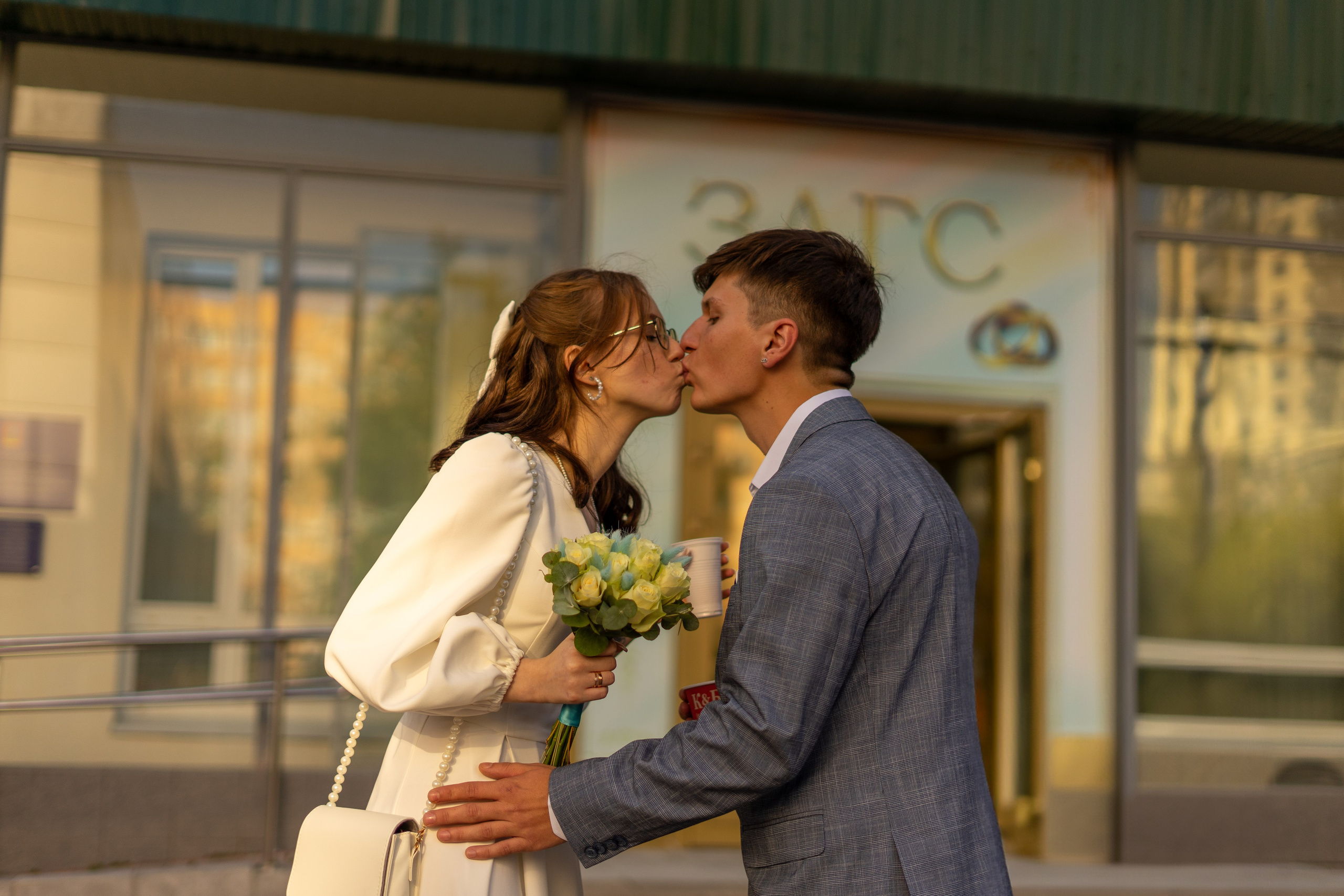 Молодожены целуются возле загса