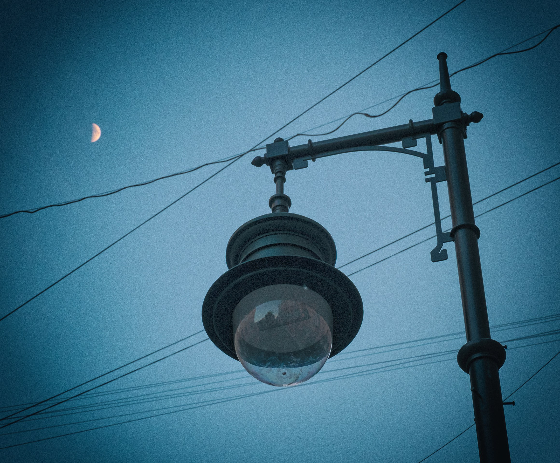 Фотография месяца на голубом небе. Фонарь и провода.