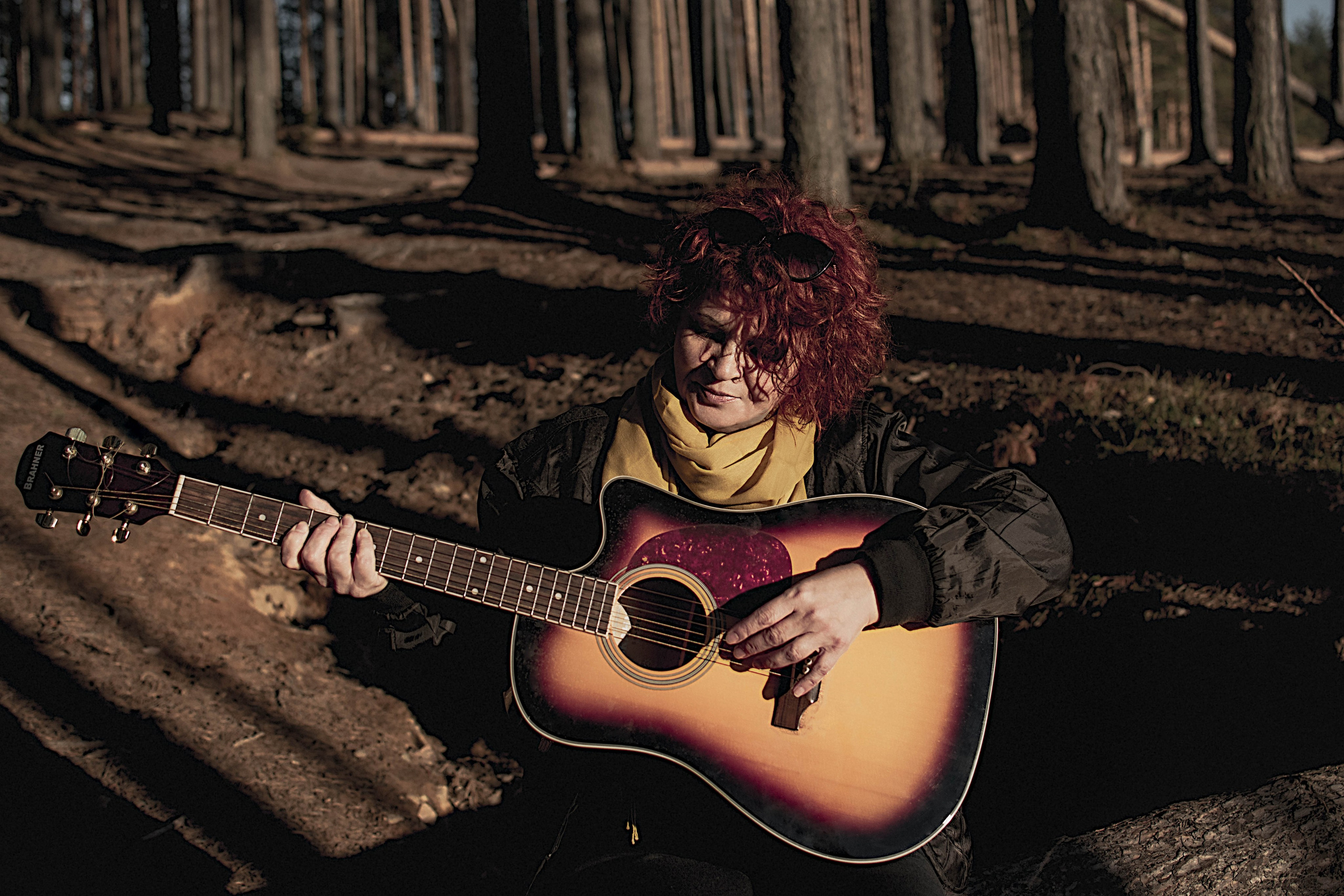 Женщина играет на гитаре в лесу