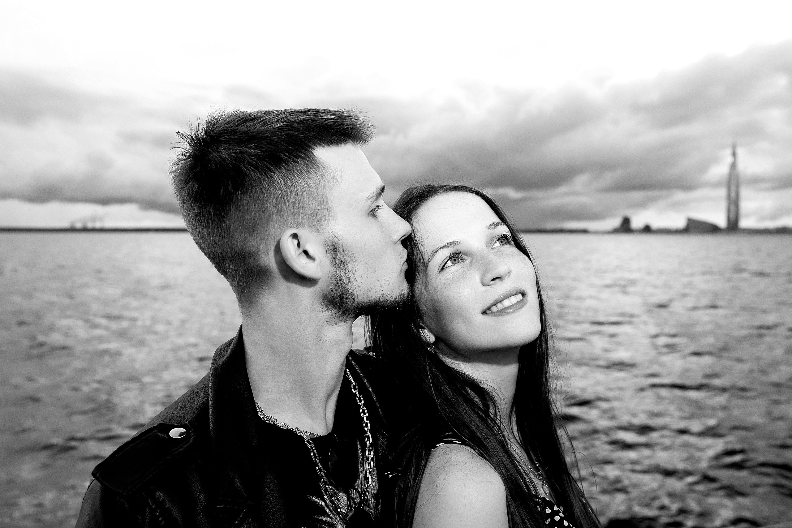 Молодой человек целует девушку на фоне Лахта-Центра на теплоходе во время экскурсии