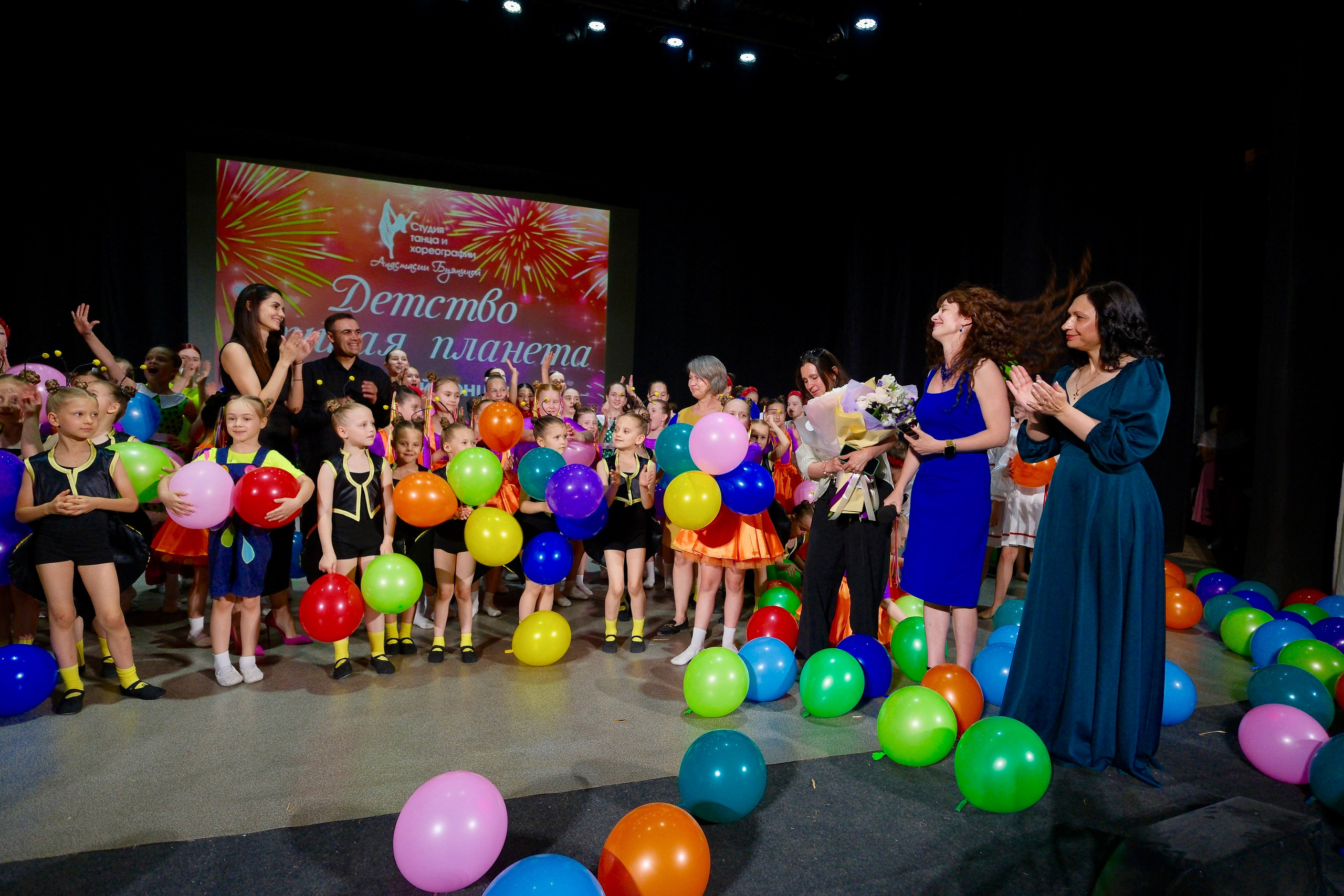 Участники детского танцевального коллектива готовятся к выходу за кулисами, поправляя костюмы и прически перед выступлением