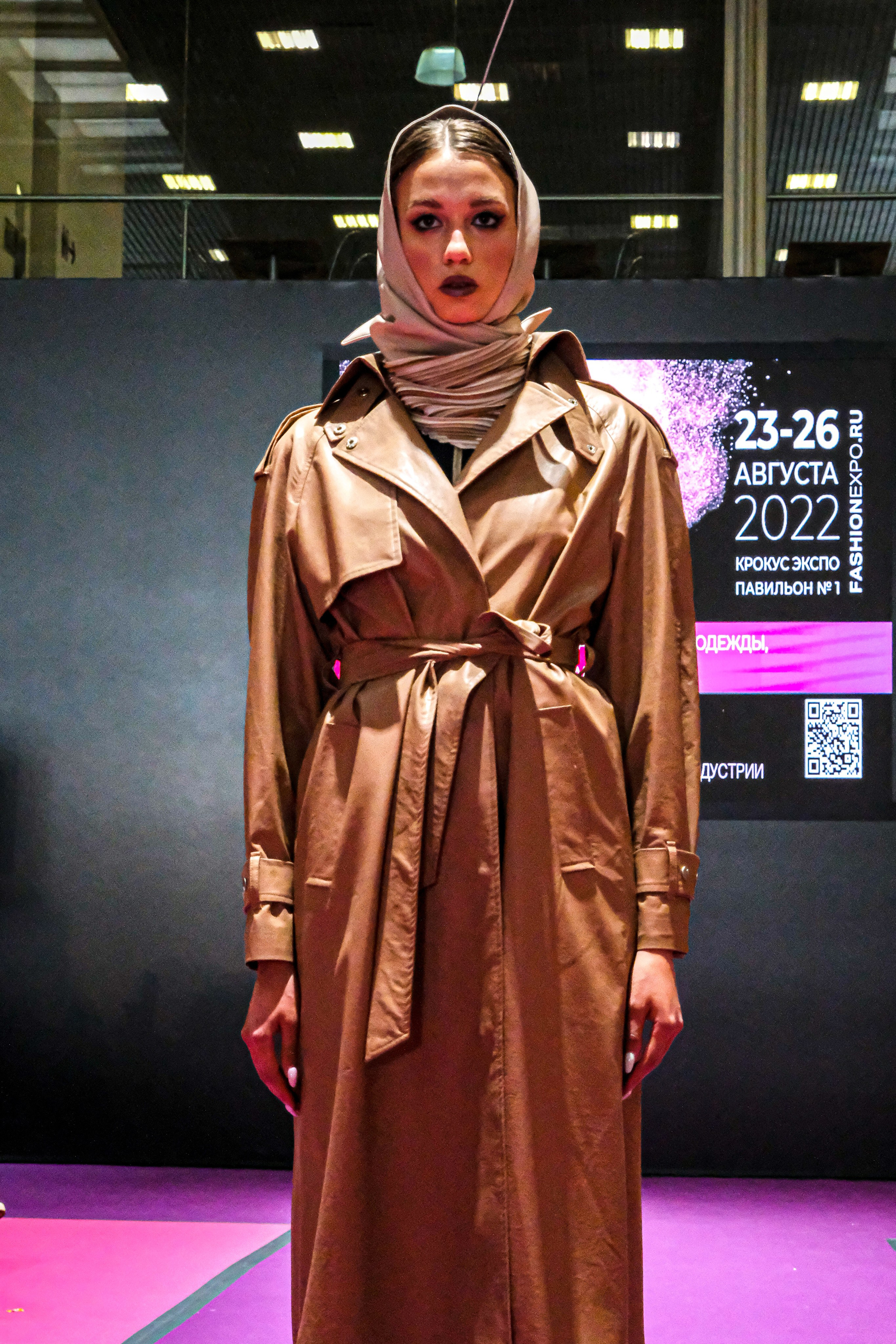  "Модели в ярких нарядах проходят по подиуму во время показа мод, освещенные яркими софитами и окруженные восторженными зрителями."