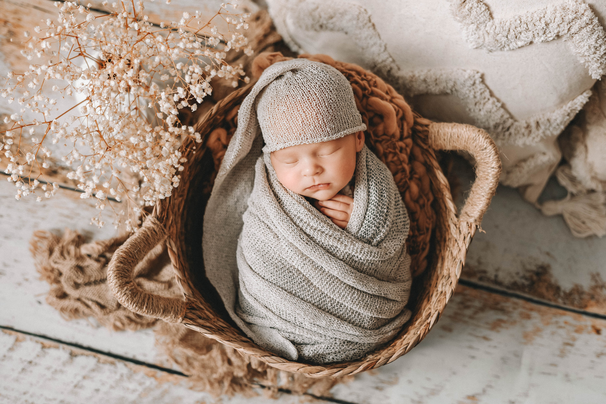 Красивая композиция с новорожденным в корзине на фоне нежных пастельных цветов