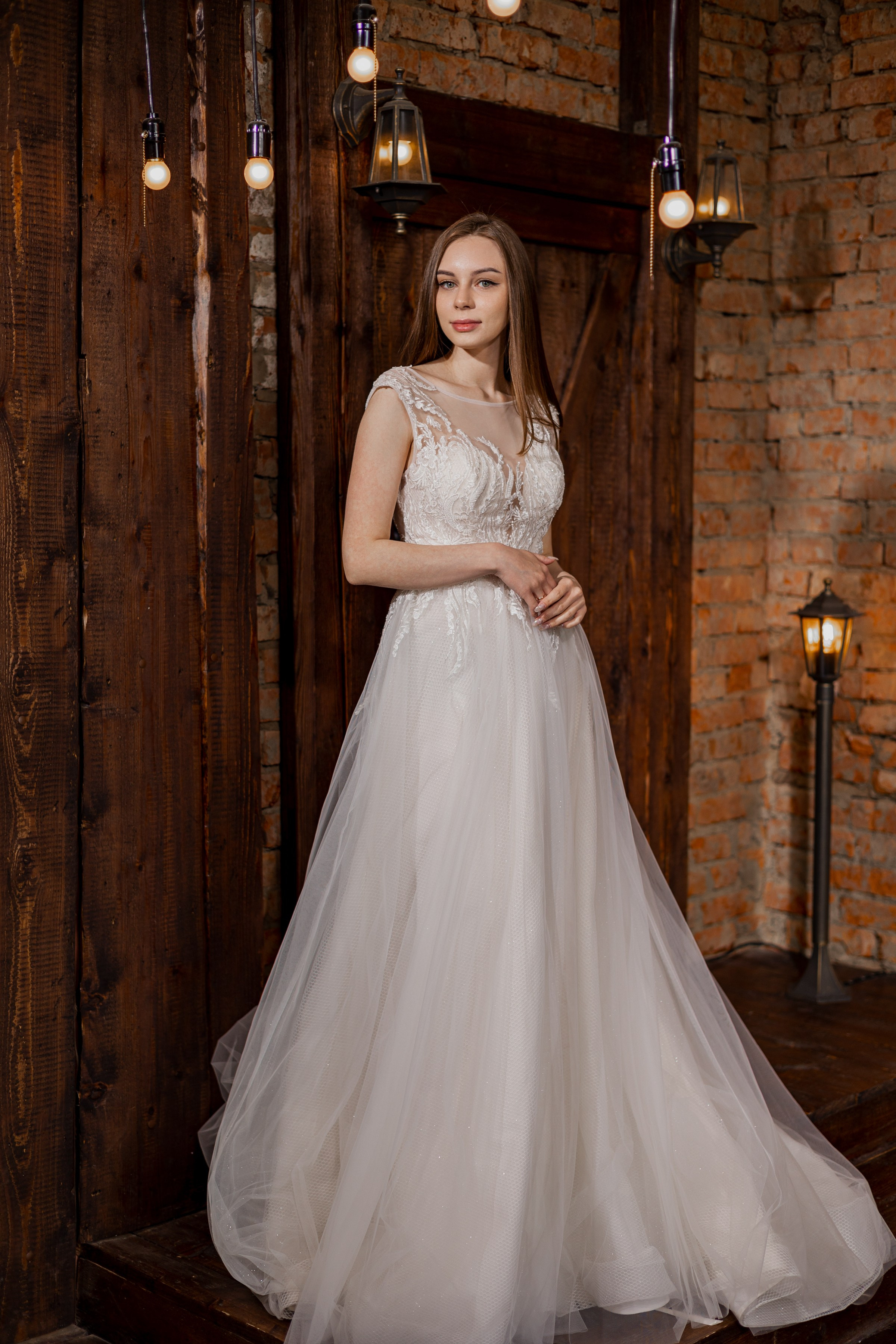 Свадебная фотография девушка в длинам платье стоит на фоне деревянные двери и лампочек хорошо освещена портрет Кемерово