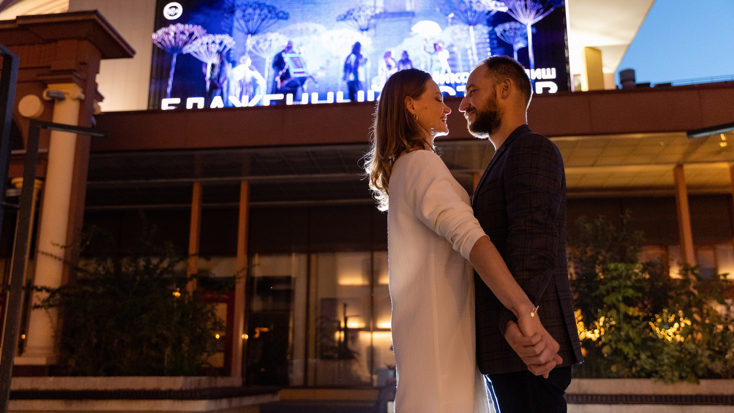 Молодые жених и невеста смотрят друг на друга перед зданием Театра.