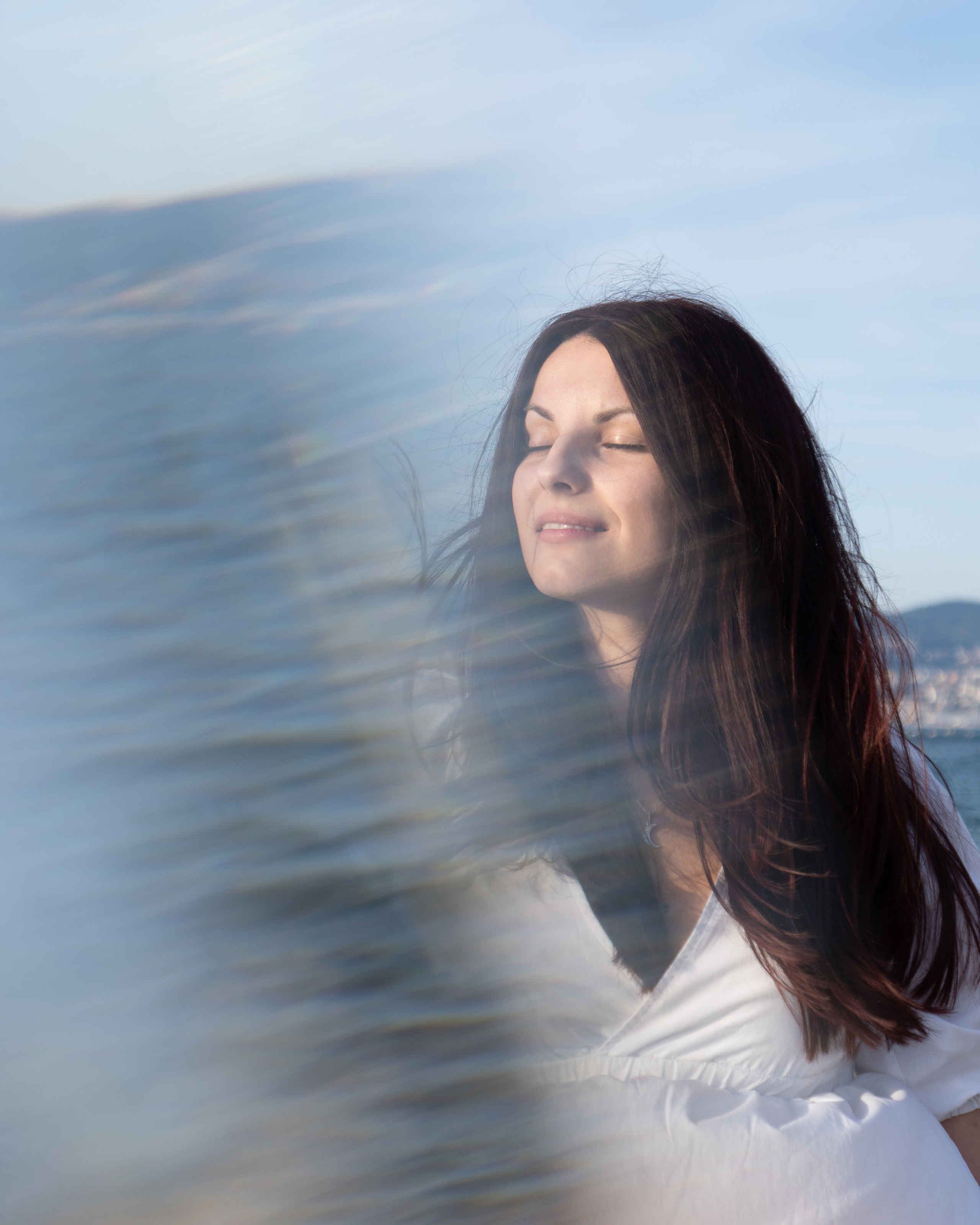 Ritratto di donna, in riva al mare sotto la luce naturale con riflessi del mare