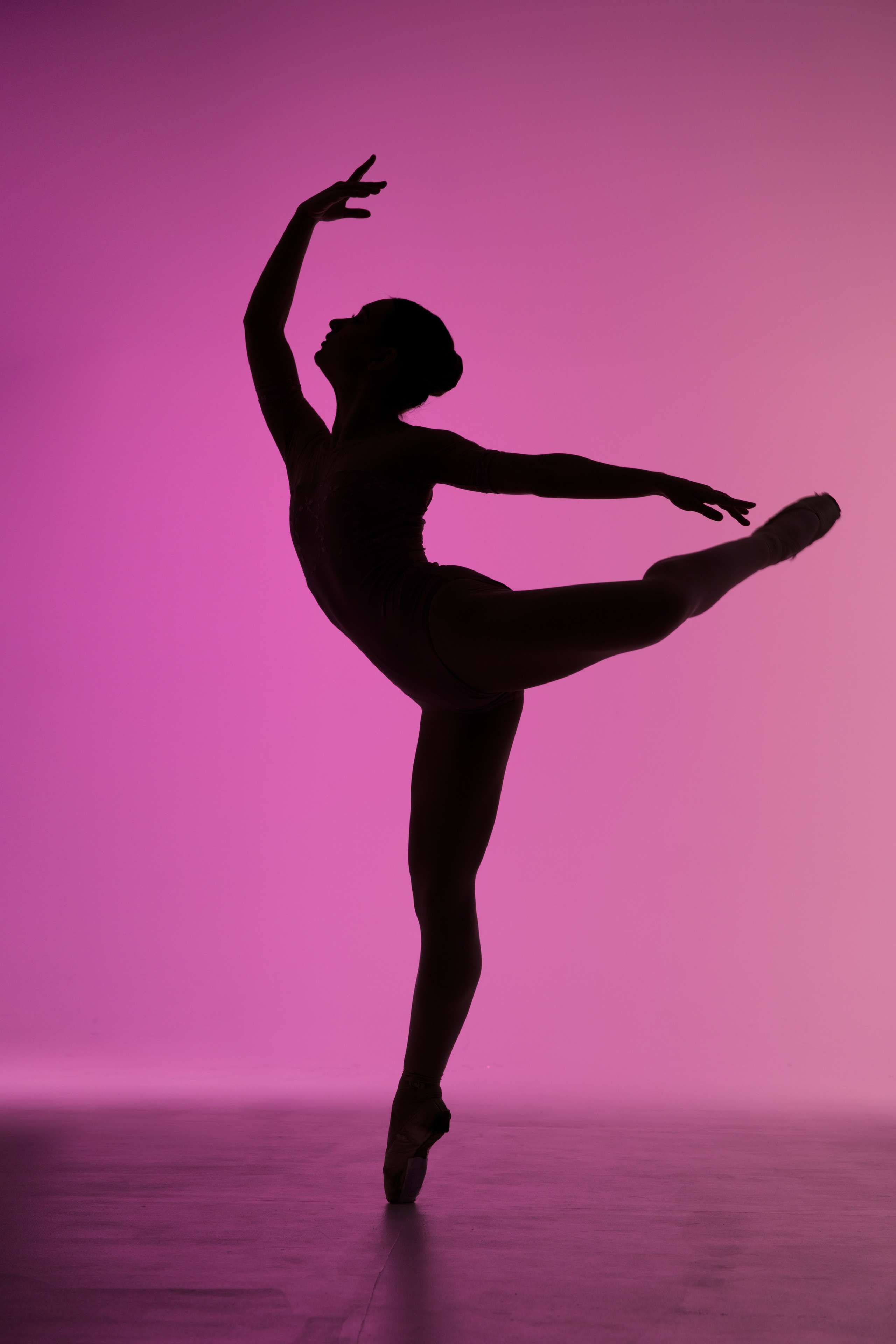 Эстетика балета: силуэт балерины на пуантах на розовом фоне.