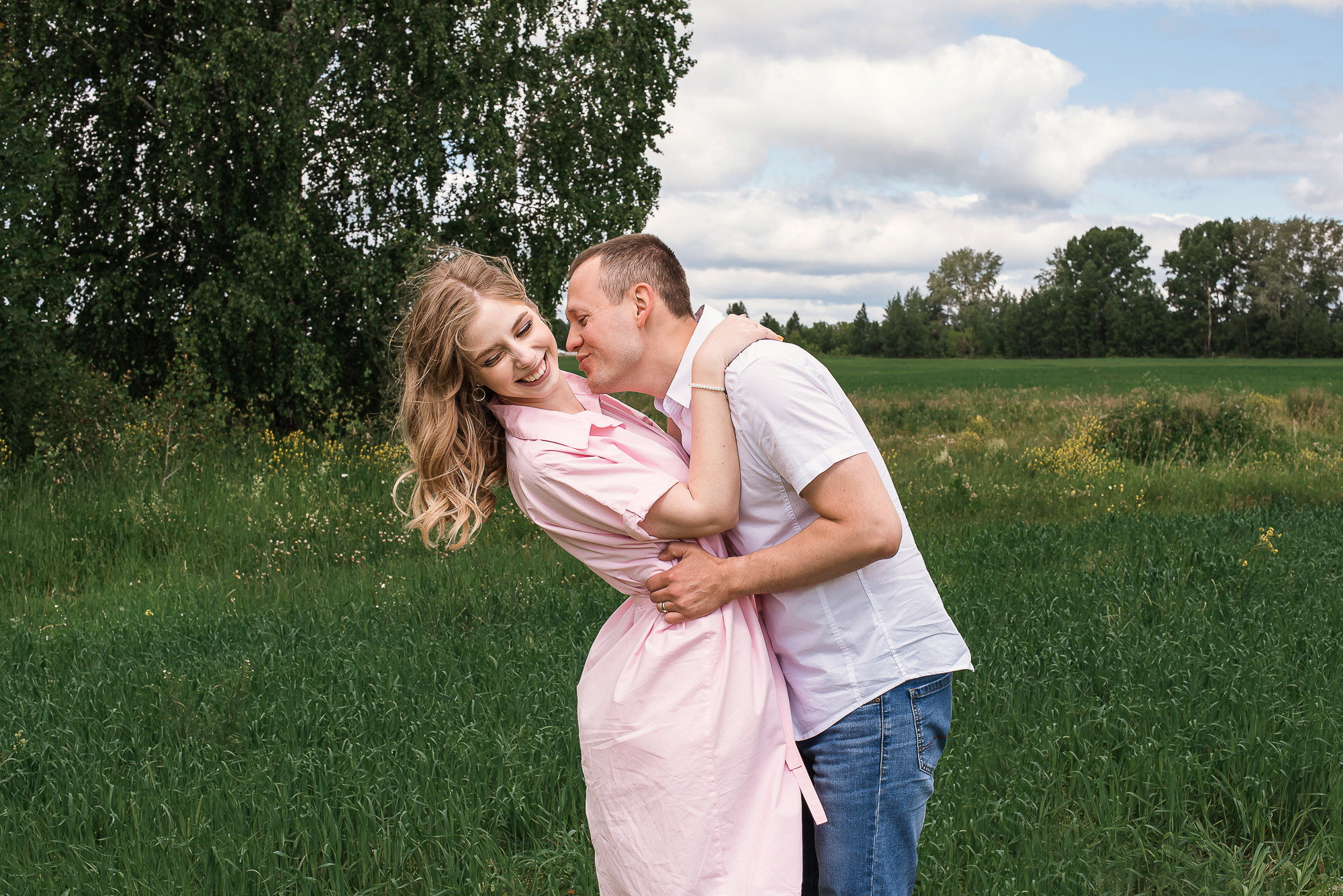 девушка в розовом платье, парень в рубашке стоят на фоне зеленых деревьев, фотосессия в поле, фотосессия летом