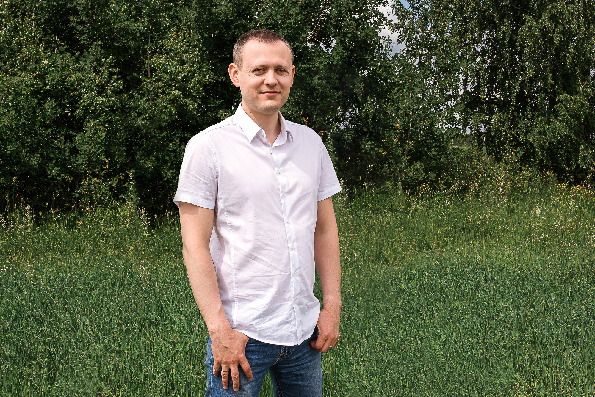 парень в рубашке на фоне зеленых деревьев, фотосессия летом, фотосессия в поле