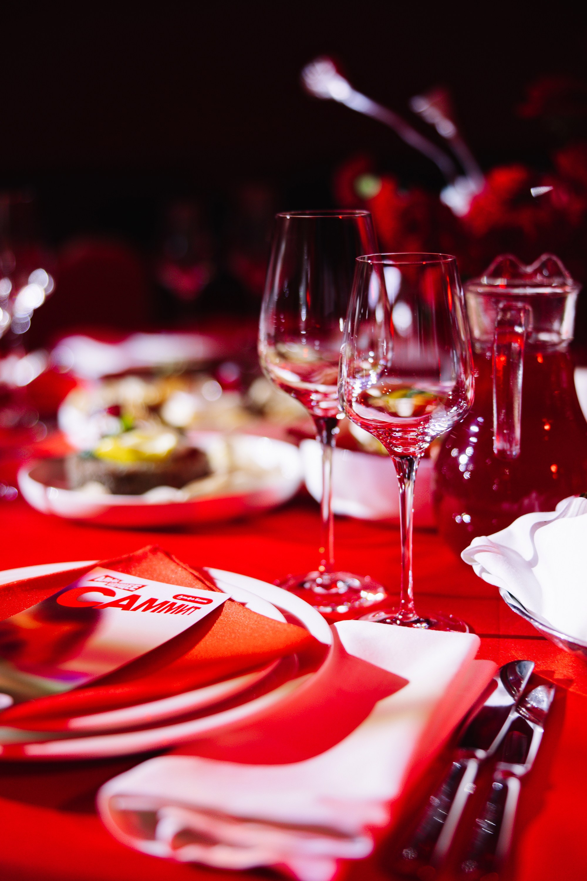 Детали стола: Крупный план бокалов и праздничной раскладки меню на вечернем банкете.