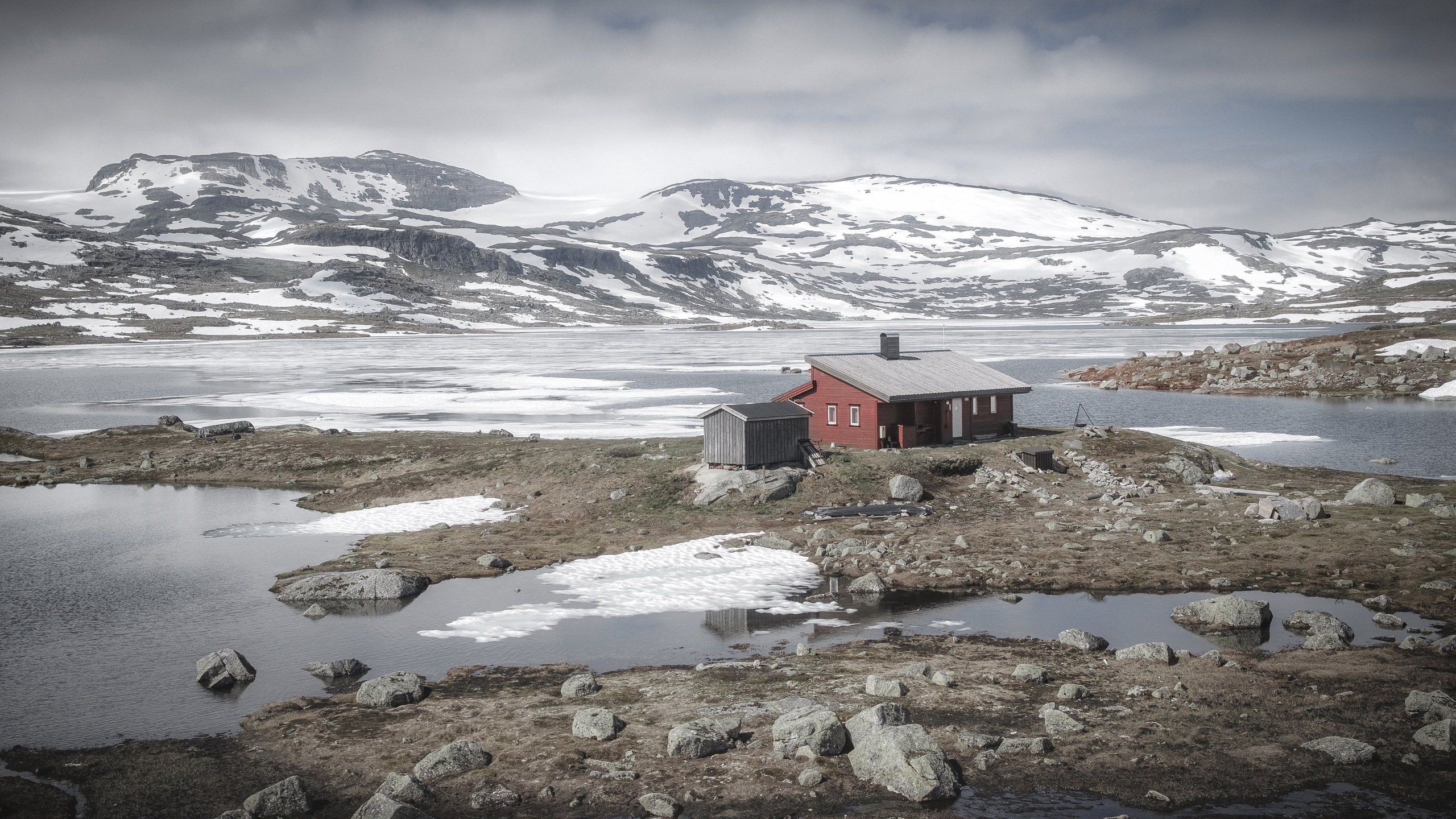 Одинокий домик на фоне гор и тающего снега