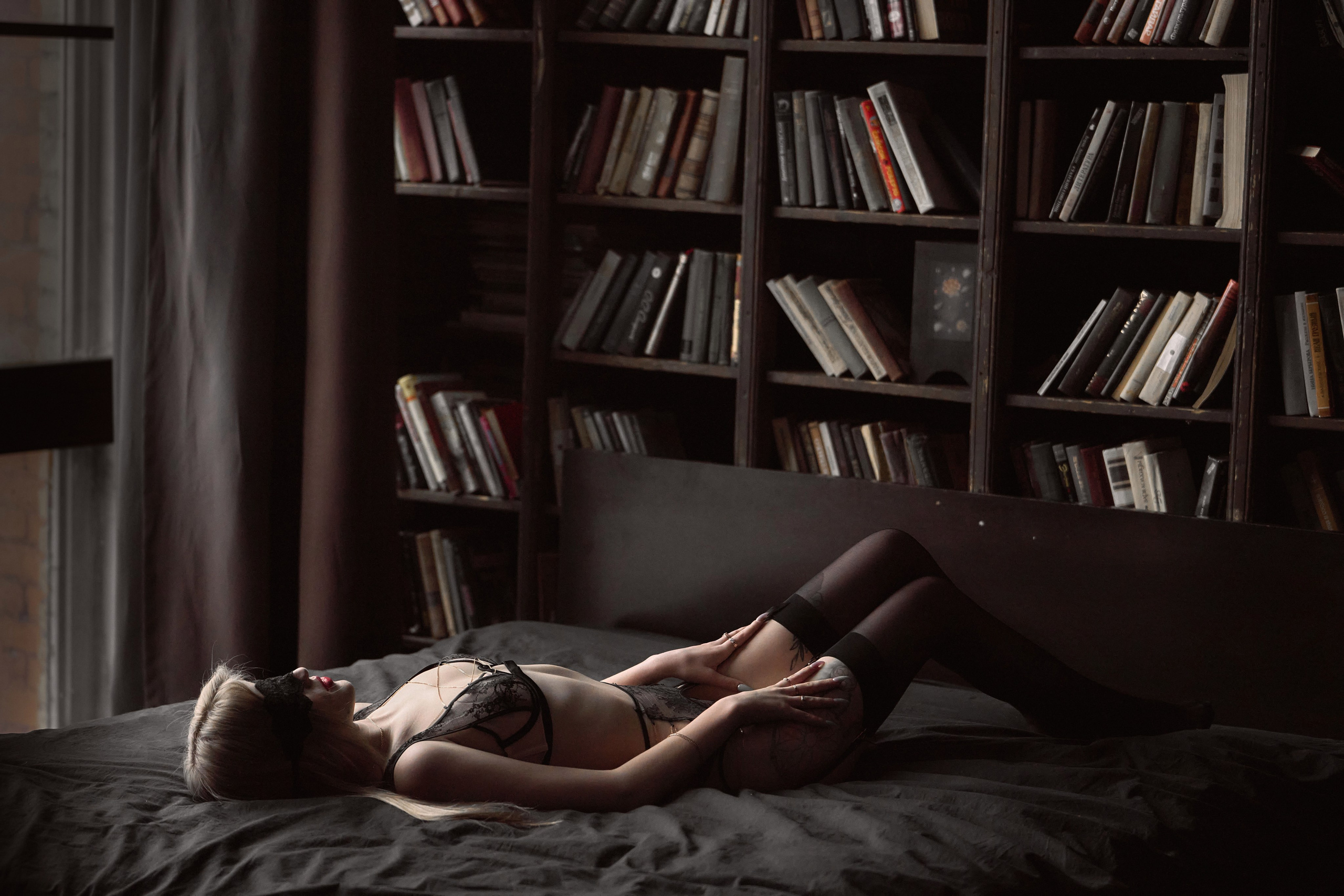 девушка в нижнем белье лежит на кровати во время эротической фотосессии