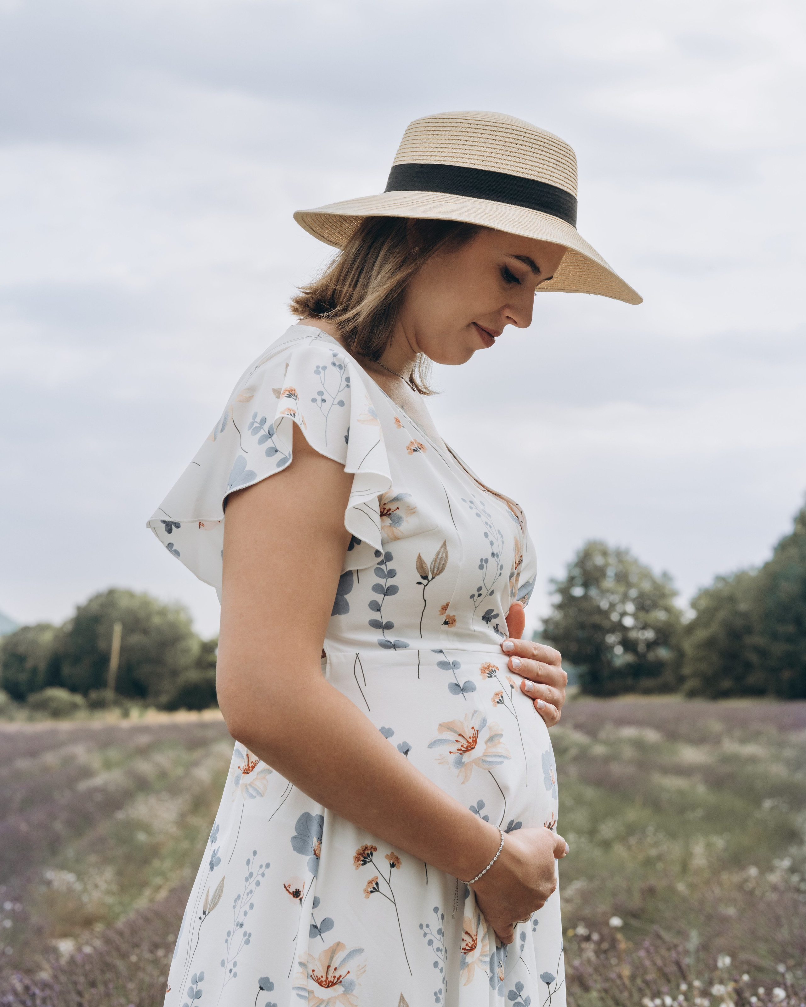 Future maman regardant son ventre dans un champ, séance grossesse dans le Gard