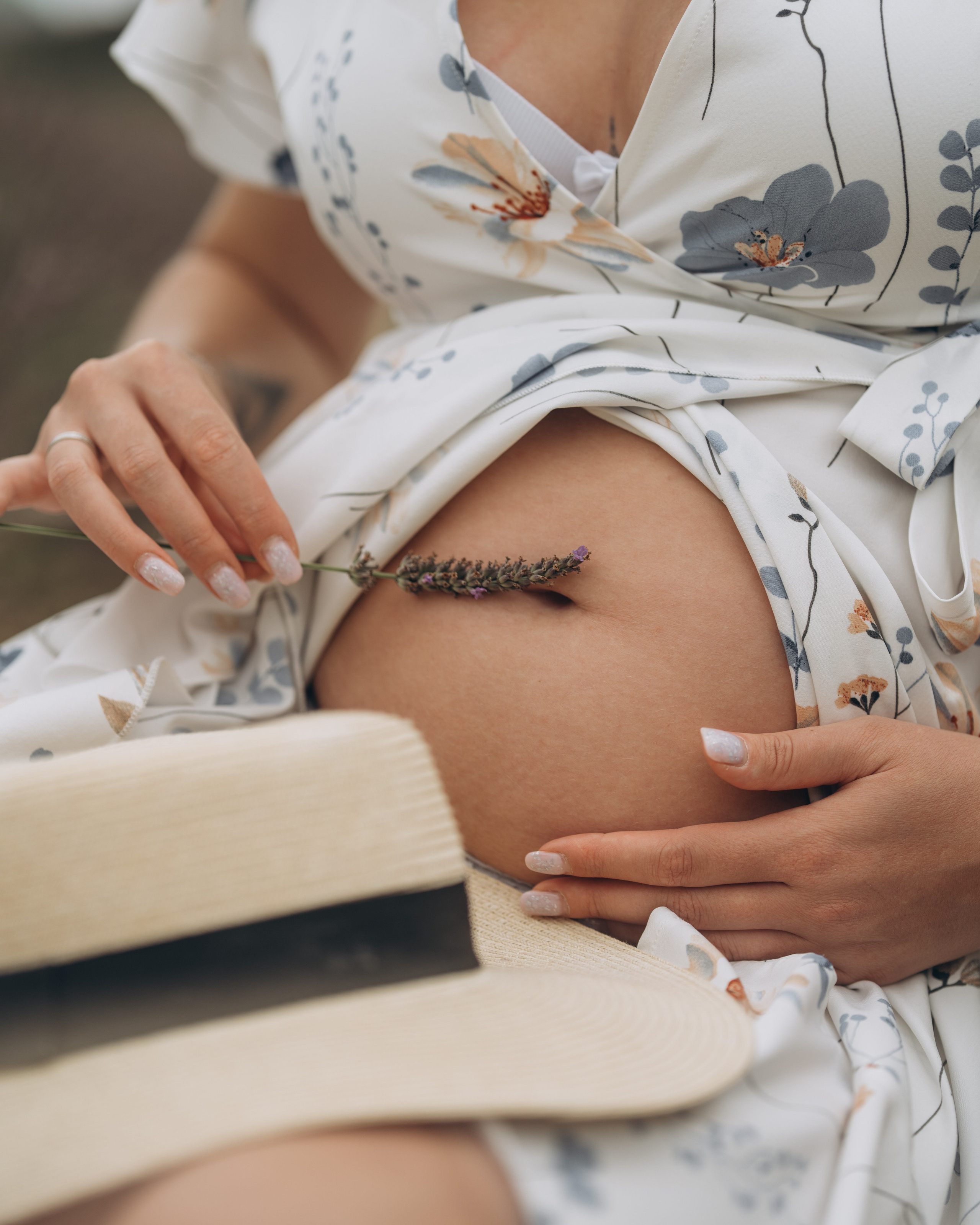 Ventre de femme enceinte et chapeau posé sur ses genoux, séance grossesse près de Nîmes