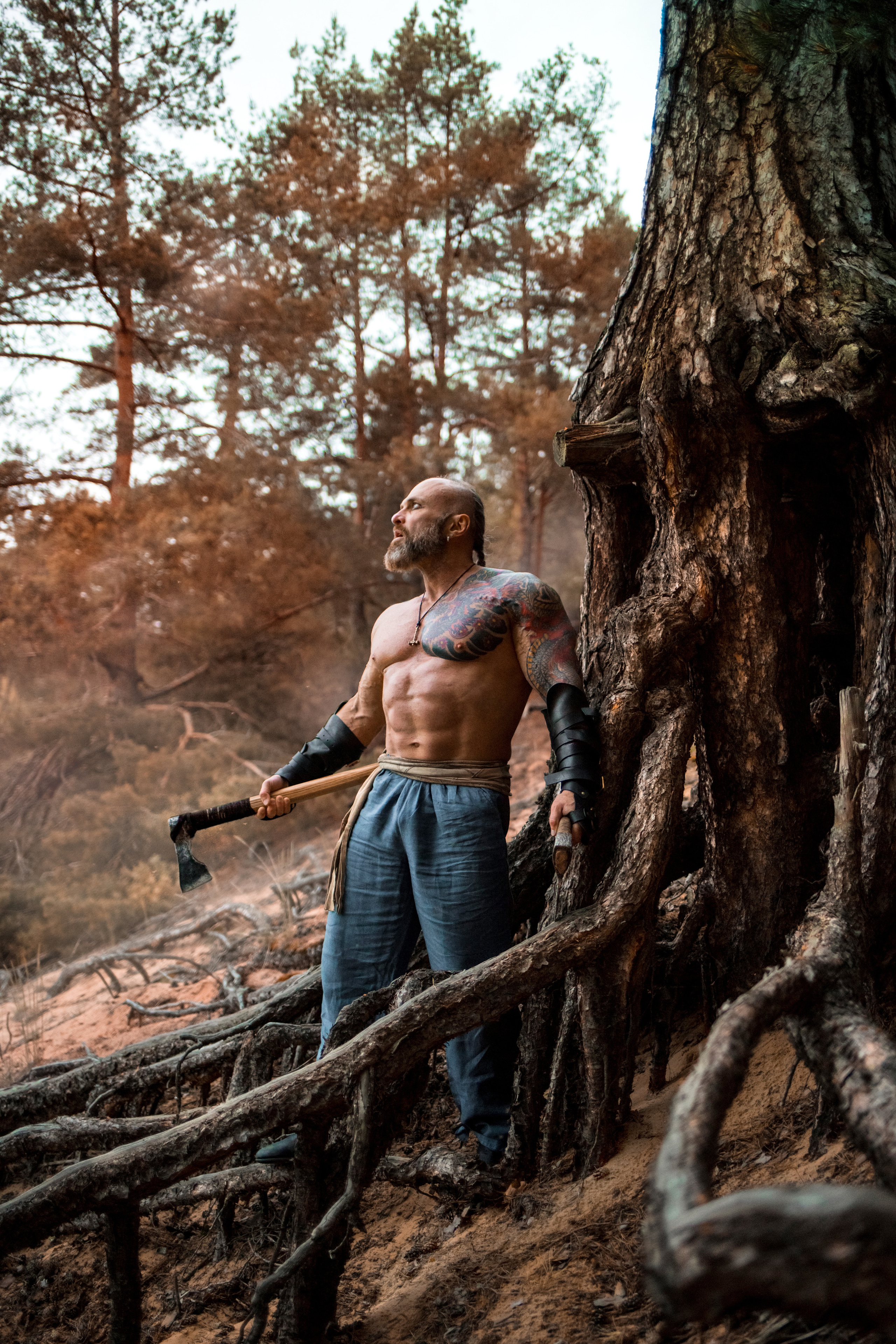 бодибилдер фотосессия в стиле викинги. Ночная фотосессия среди корней старых деревьев с дымом и огнем.