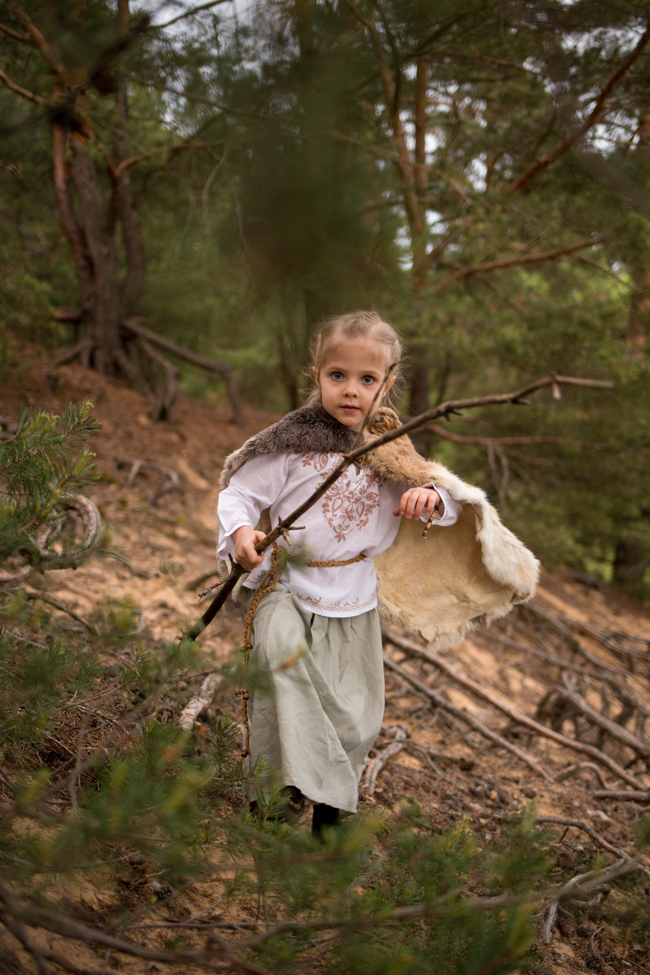 Тематическая фотосессия среди корней старых деревьев с дымом и огнем. Девочка среди корней деревьев