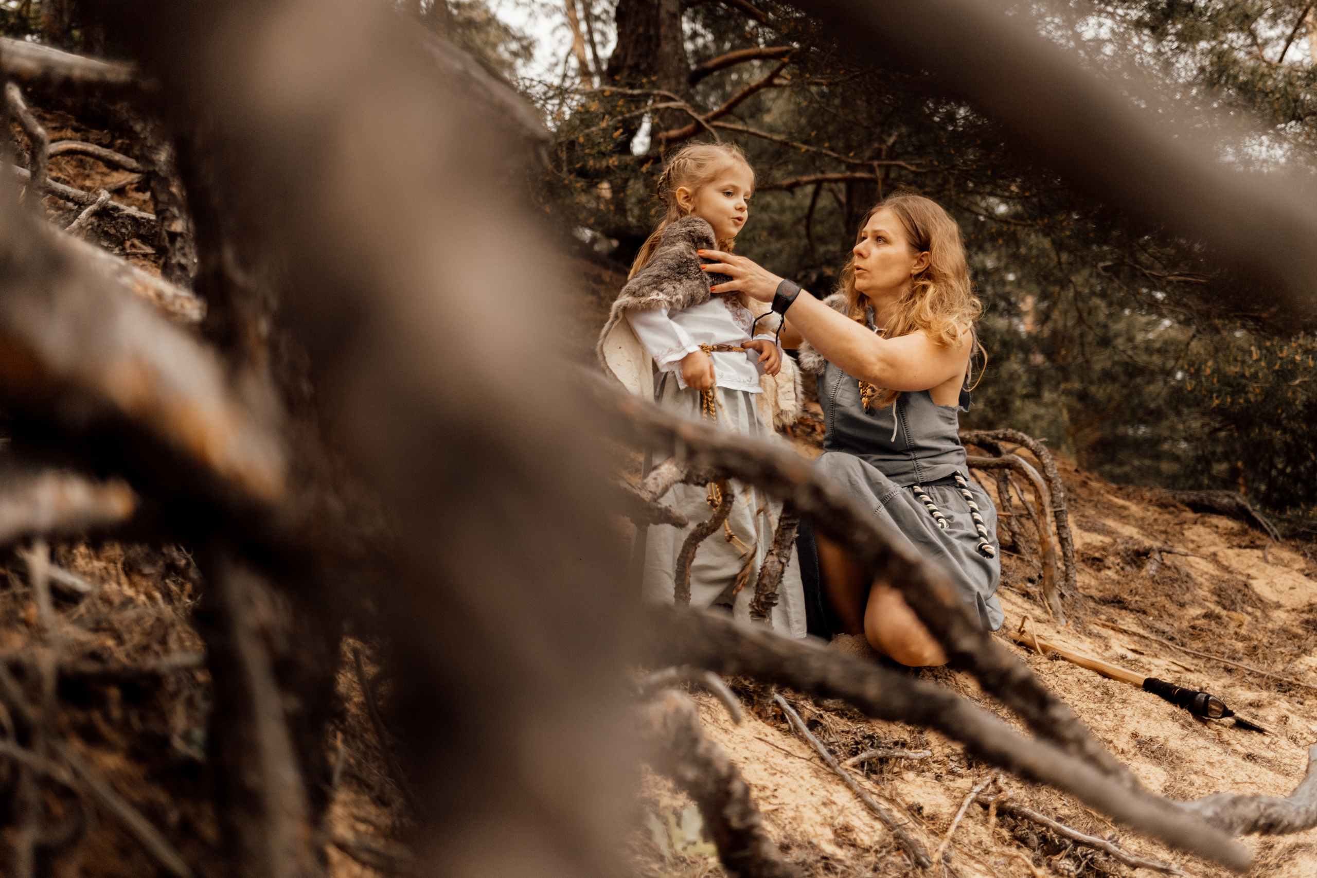 Тематическая фотосессия среди корней старых деревьев с дымом и огнем. Мама и дочь среди корней деревьев