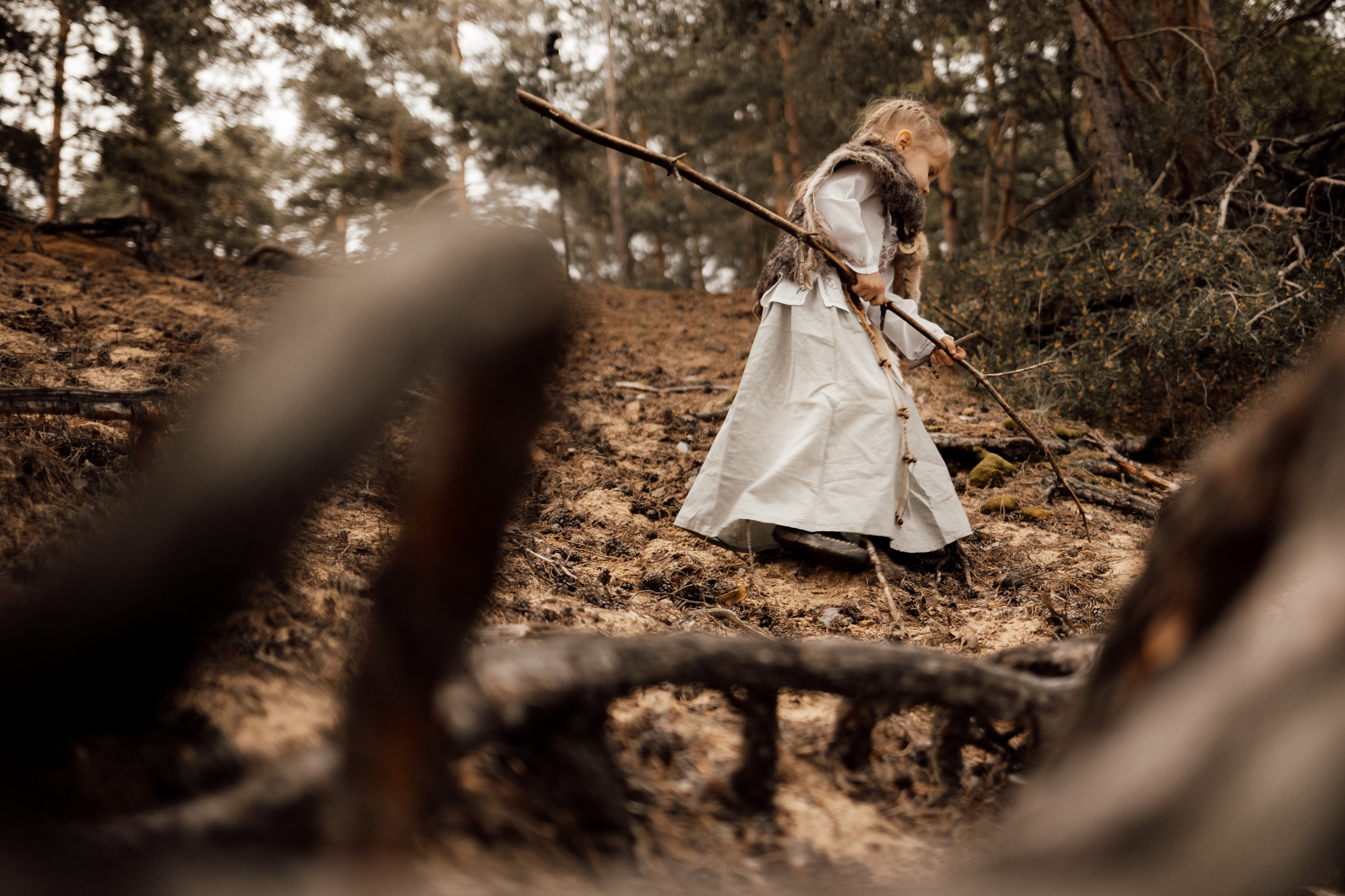 Тематическая фотосессия среди корней старых деревьев с дымом и огнем. Девочка среди корней деревьев