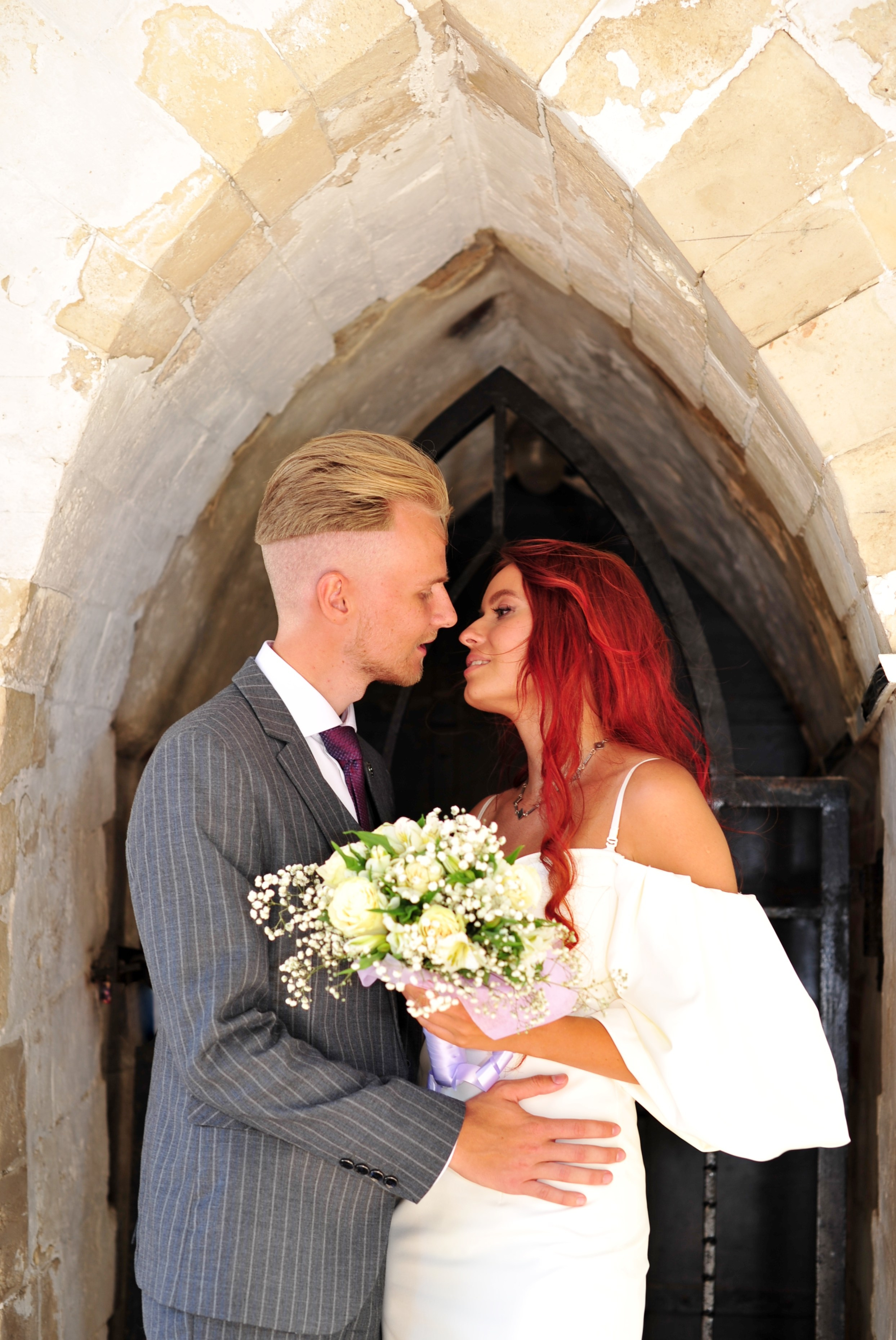 Свадьба в Царицыно летом, молодожены смотрят друг на друга и обнимаются в арке моста