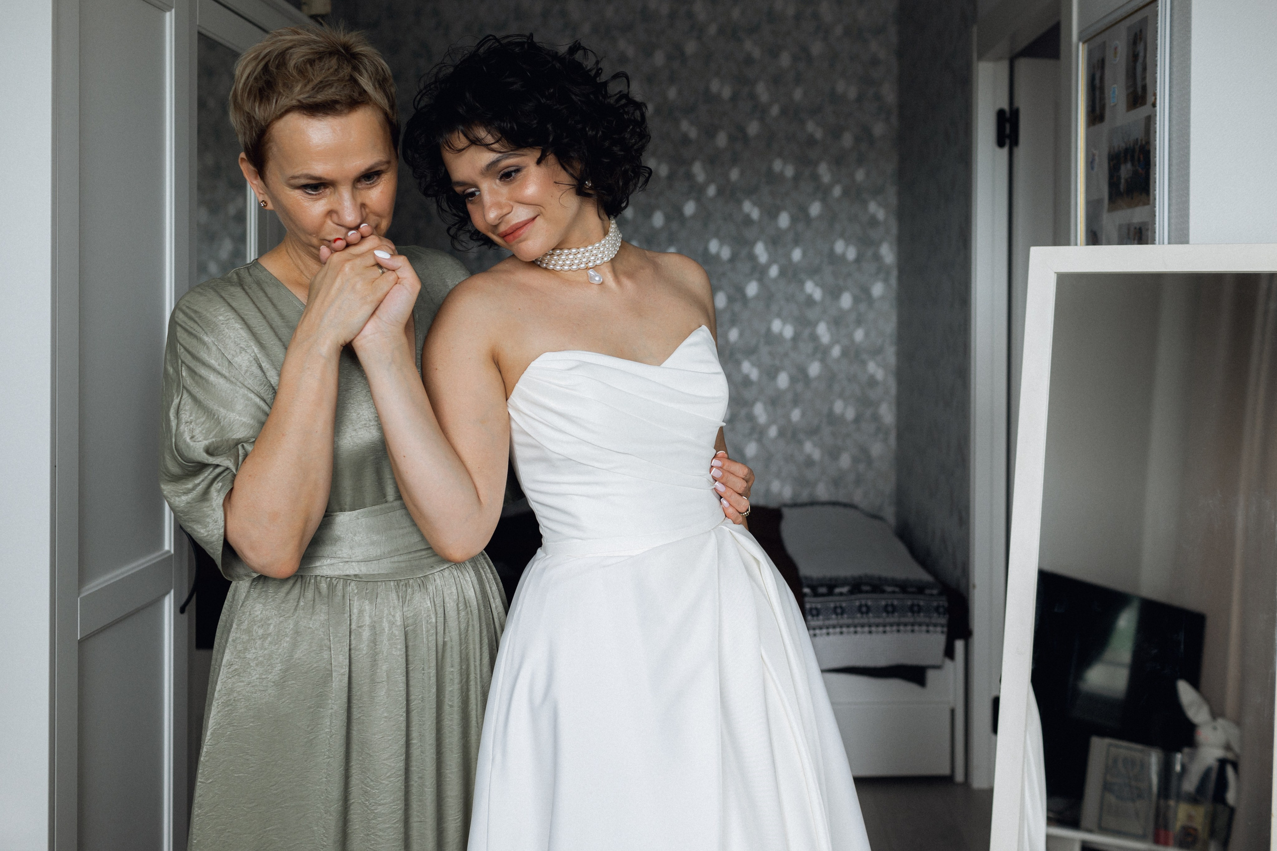 Трогательный момент перед свадьбой: мама нежно целует руку дочери в атласном свадебном платье от салона NATALIE L