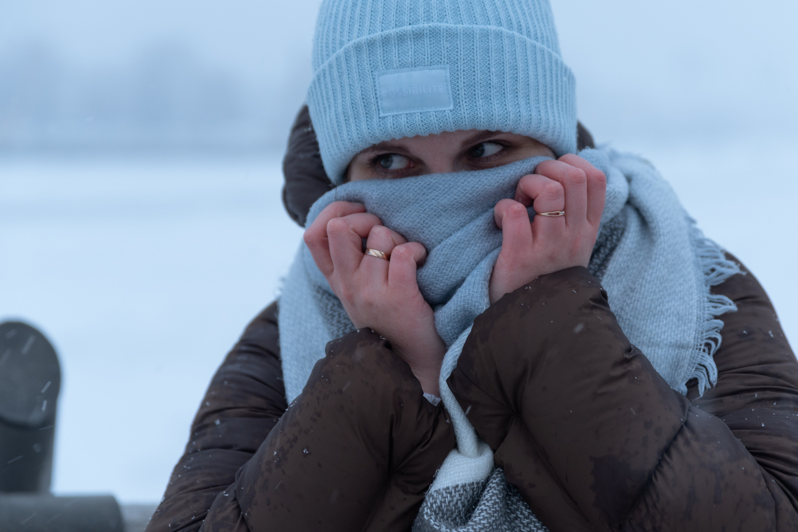 Девушка в вязанной шапке, крупный портрет. Закрывает лицо шарфом, видно только глаза.