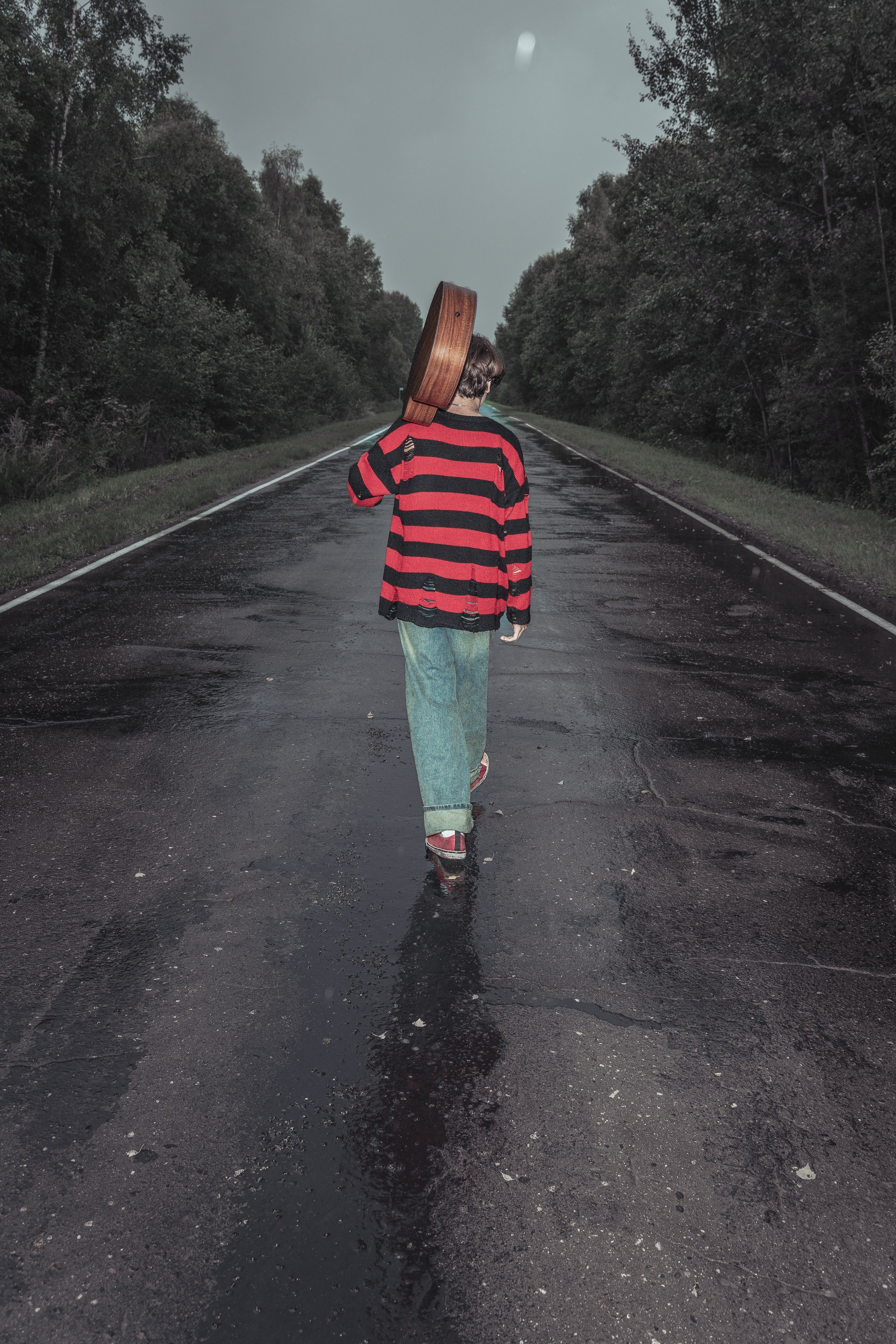 Молодой человек идет по дороге в стильной одежде