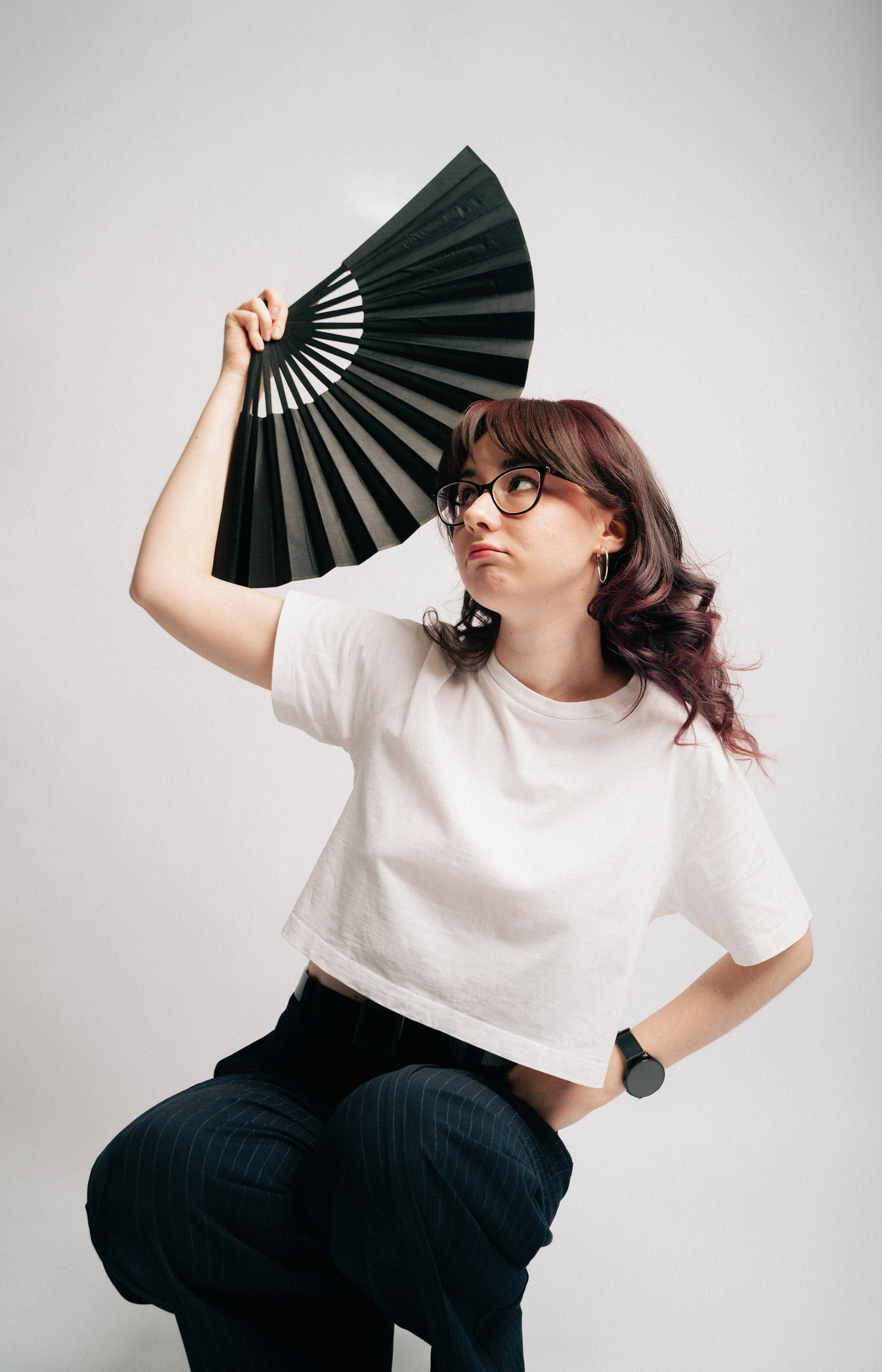 Портрет девушки в очках, снятый на белом фоне в динамичной позе.