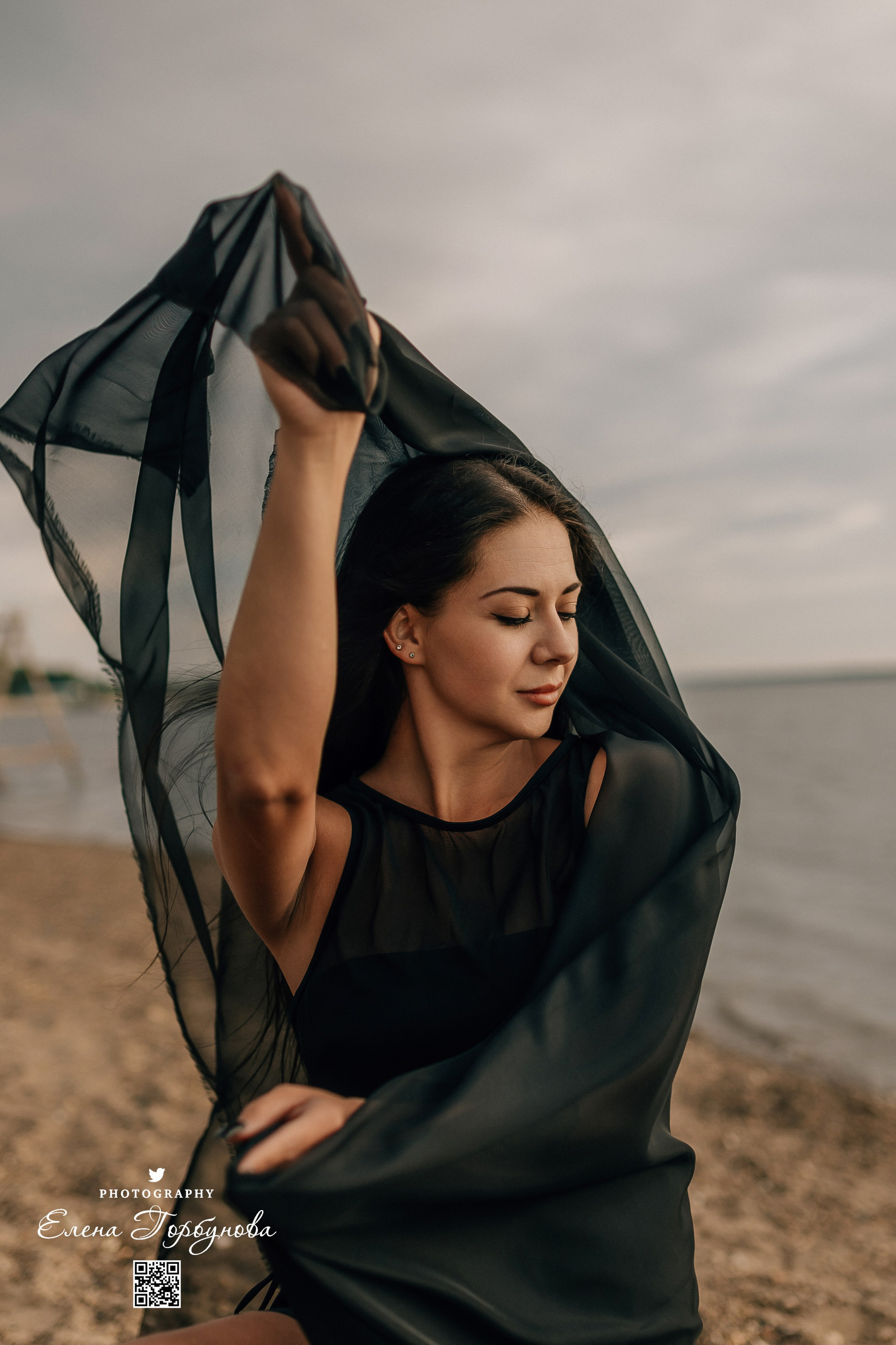 Фотосессия с черной тканью. Легкая черная вуаль летит на вертру. Фотосессия у реки черная серия с тканью. Девушка укуталась в черную ткань. Прогулка по набережной. Песок, речка, модель в черном. Качели над водой, Закат. Девушка лежит на песке. В зеленых деревьях