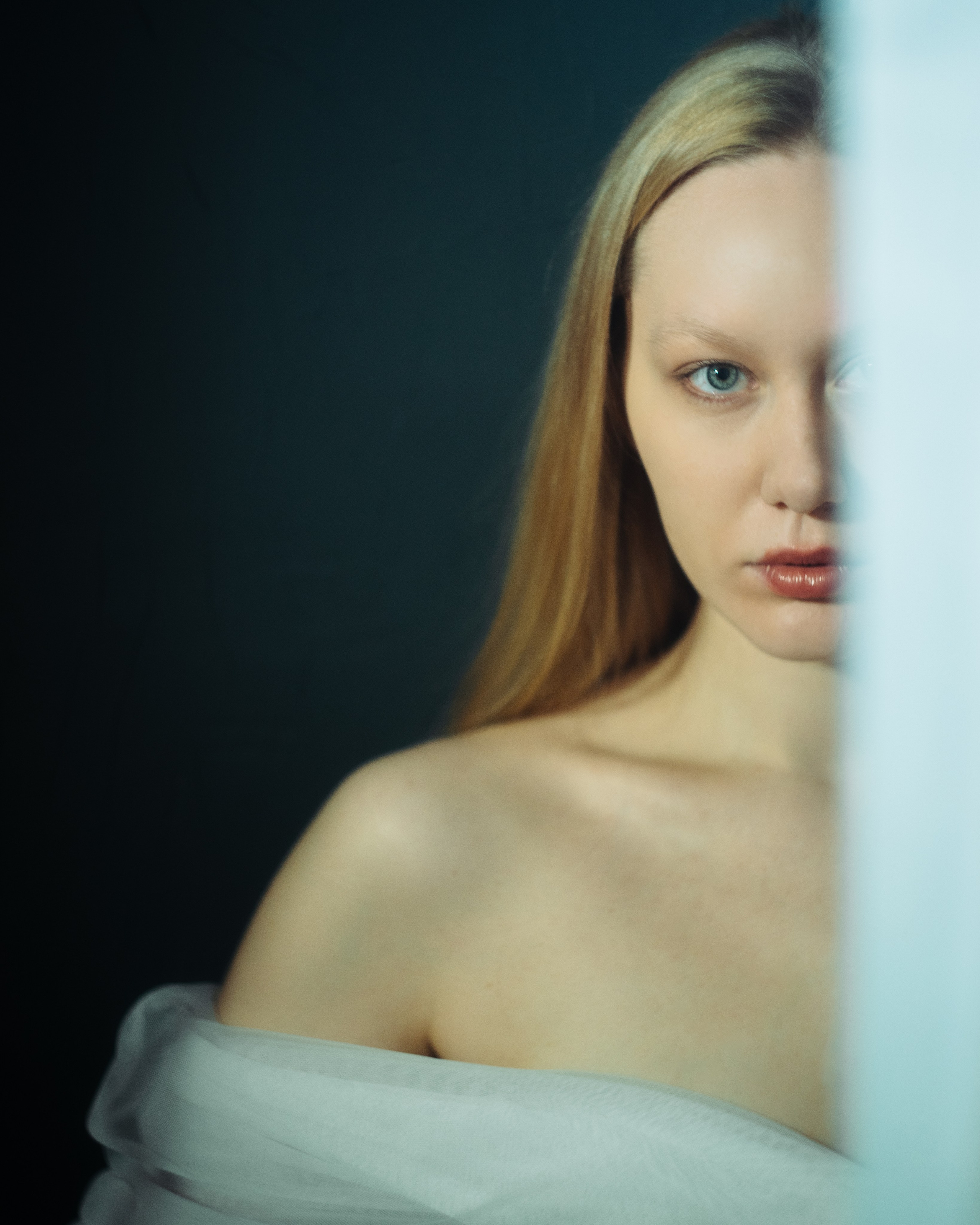 Крупный портрет девушки в студии, авторская женская фотосессия с прямым взглядом, мягким светом и темной эстетикой