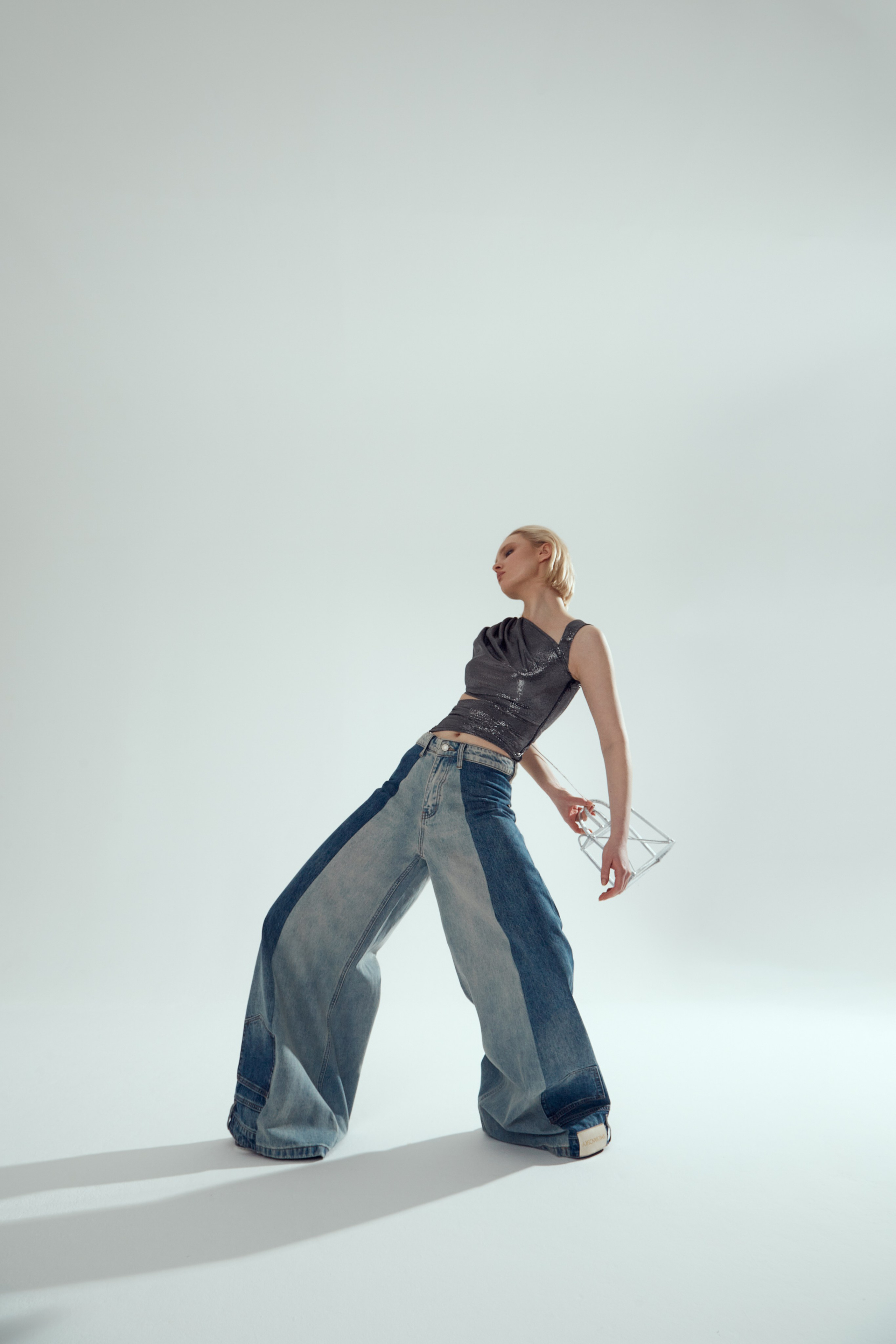 Девушка позирует в стиле high fashion в широких джинсах