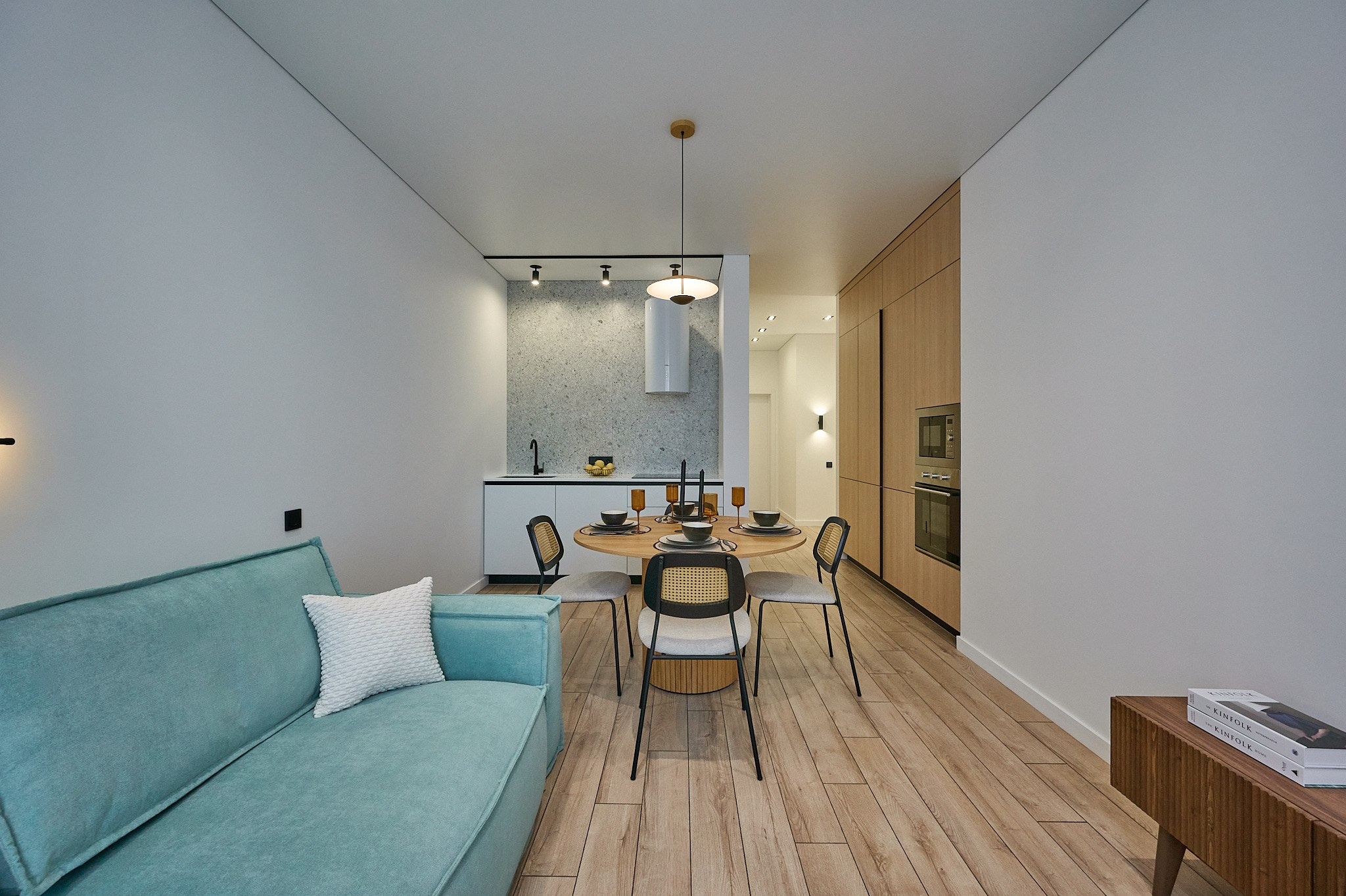 кухня светлые оттенки голубой диван коричневая полка круглый стол со стульями белые ящики и полки светлые шторы