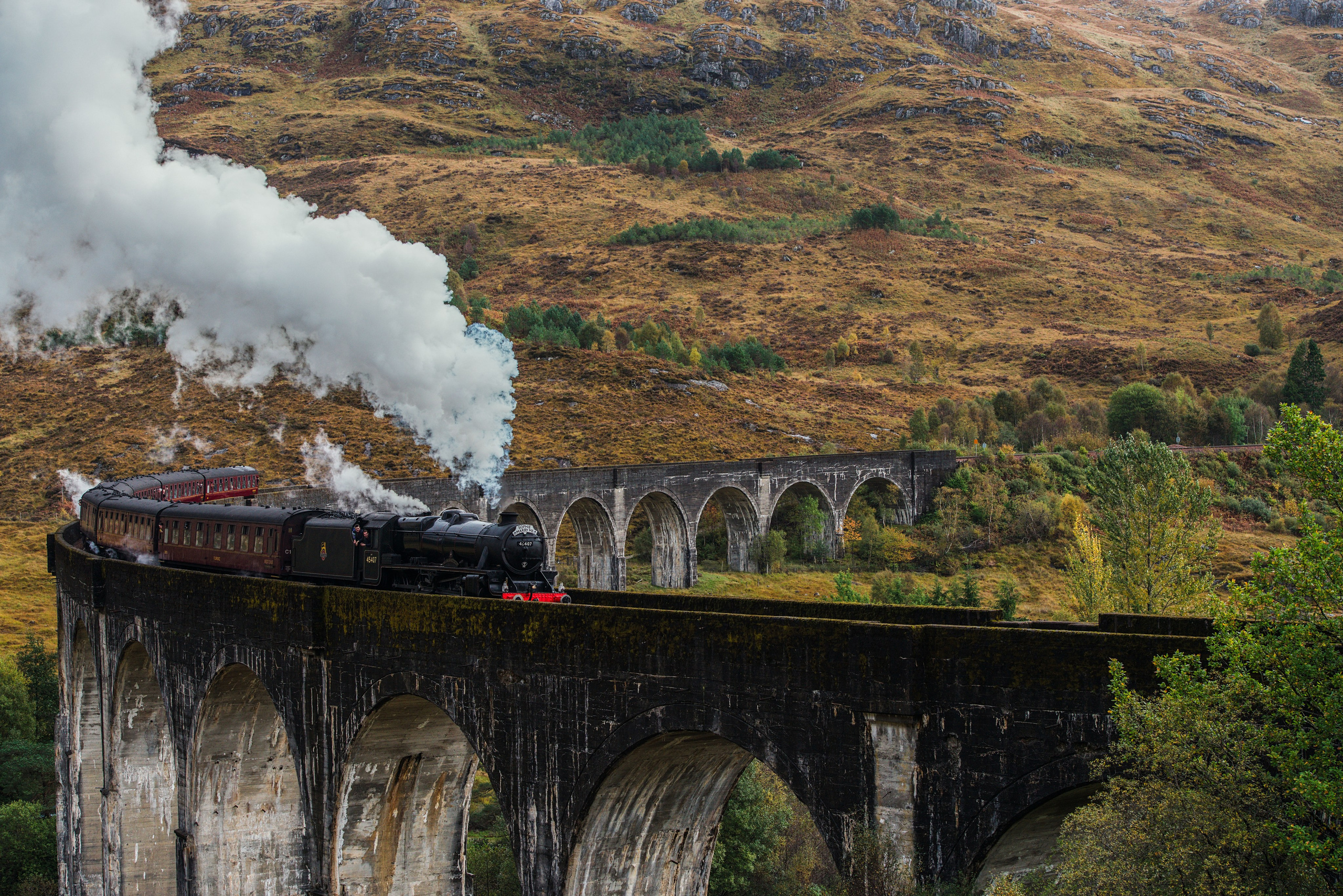  Фотография Хогвартс-экспресс  пересекающего знаменитый виадук Гленфиннан в Шотландии, драматичный вид горного пейзажа и клубов пара