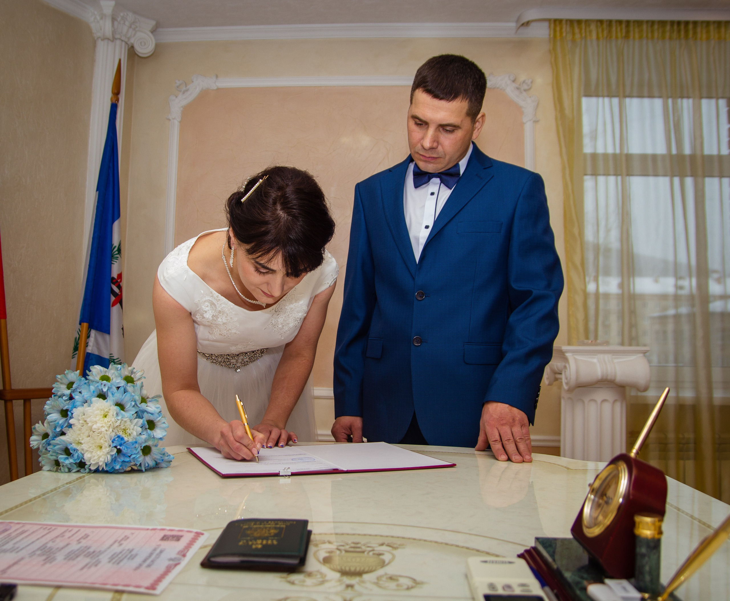 Невеста подписывает свидетельство, жених стоит рядом — торжественная часть церемонии.