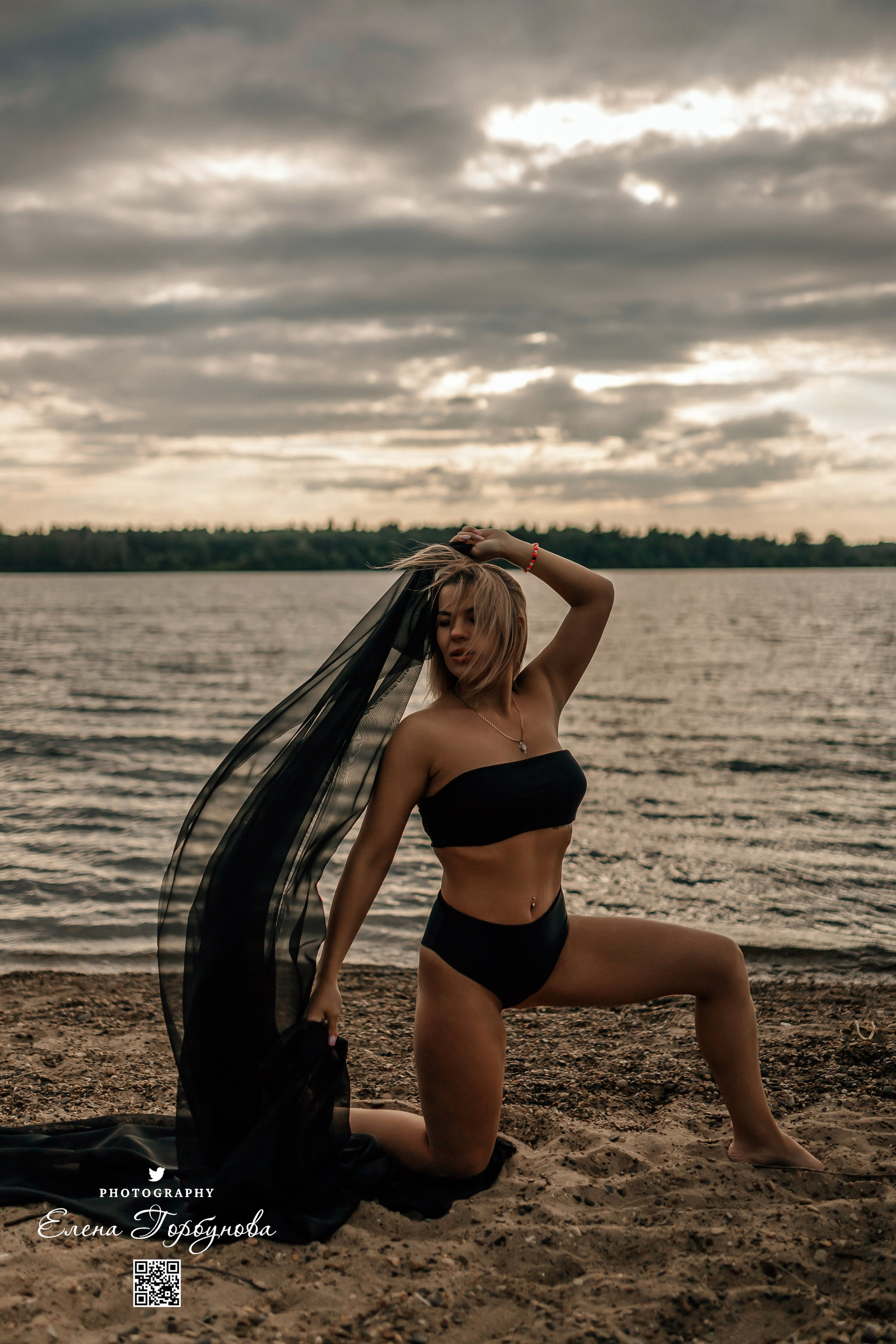 Фотосессия с черной тканью. Легкая черная вуаль летит на вертру. Фотосессия у реки черная серия с тканью. Девушка укуталась в черную ткань. Прогулка по набережной. Песок, речка, модель в черном. Качели над водой, Закат. Девушка лежит на песке. В зеленых деревьях