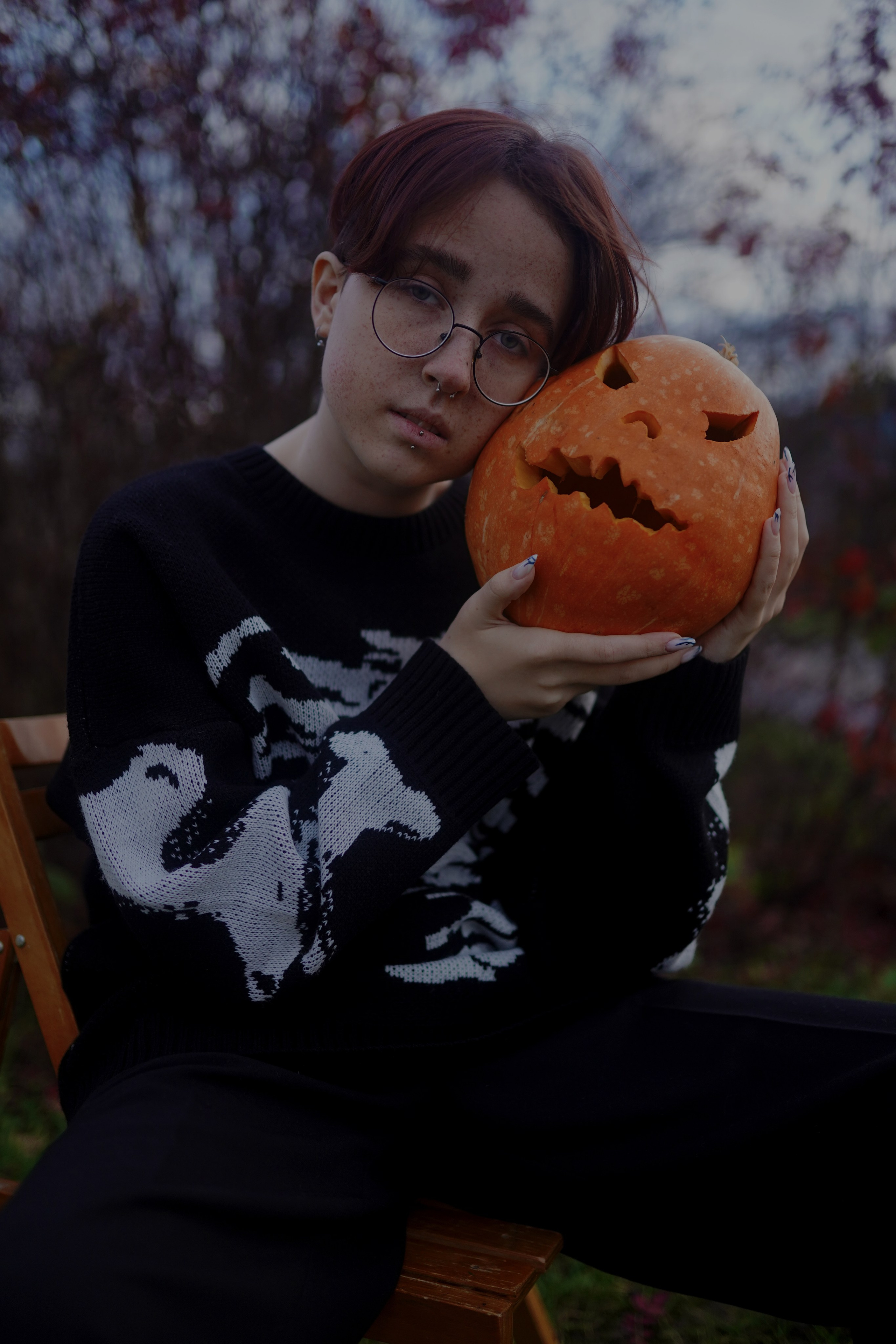 "Девушка с веснушками в образе на Хэллоуин держит резную тыкву-фонарь"