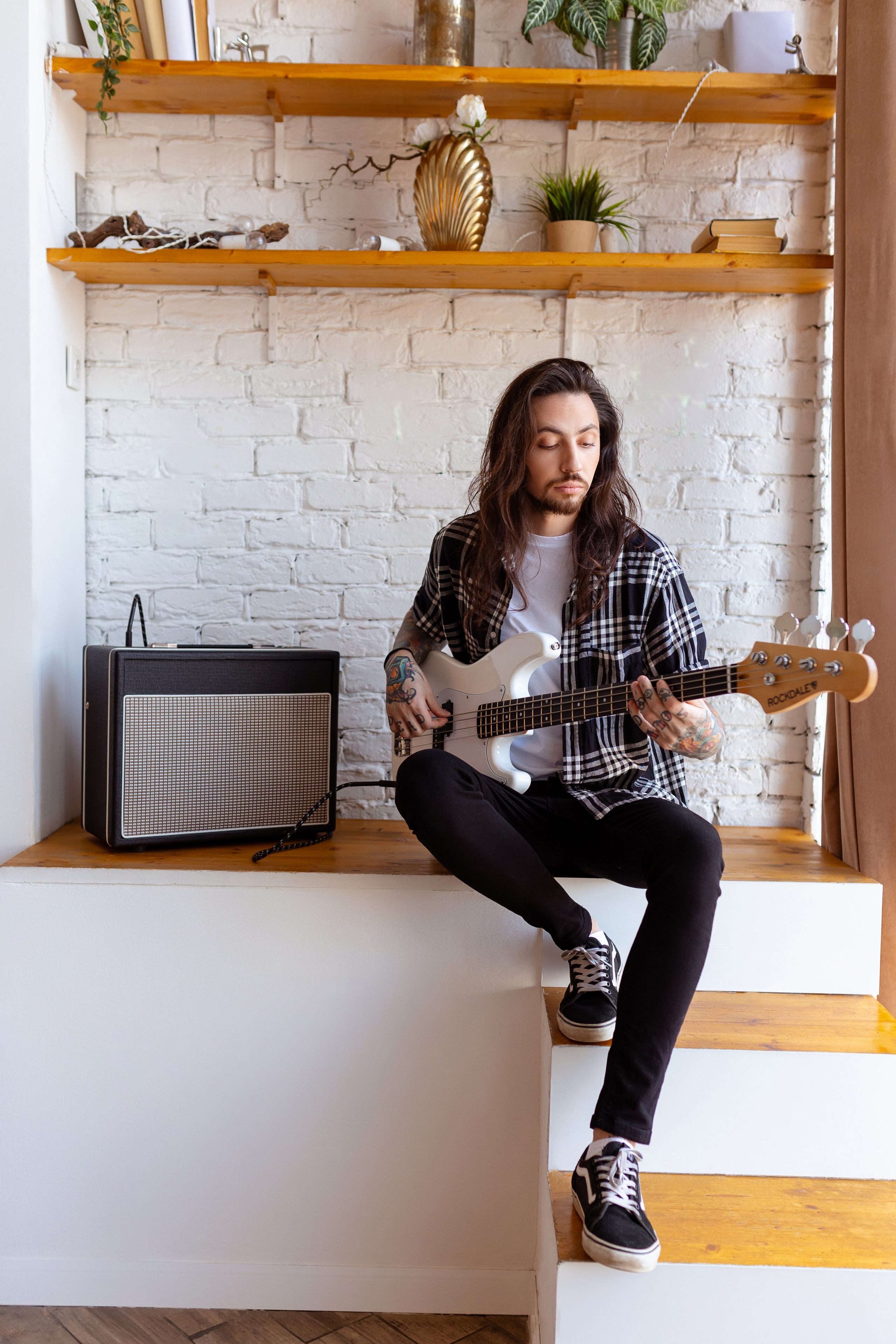 Молодой человек играет на белой электрогитаре.