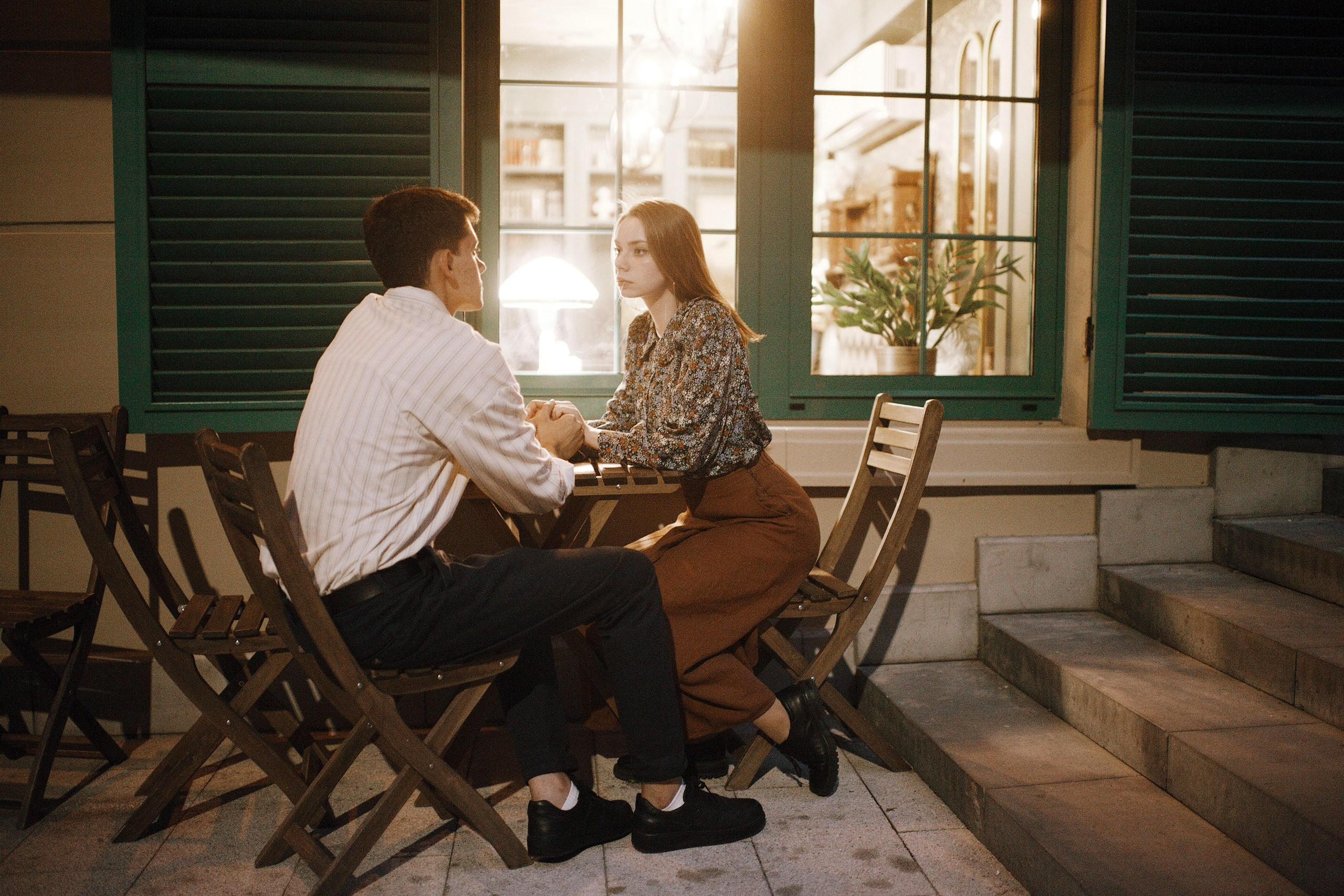 Парень с девушкой сидят на летней веранде у окна кафе