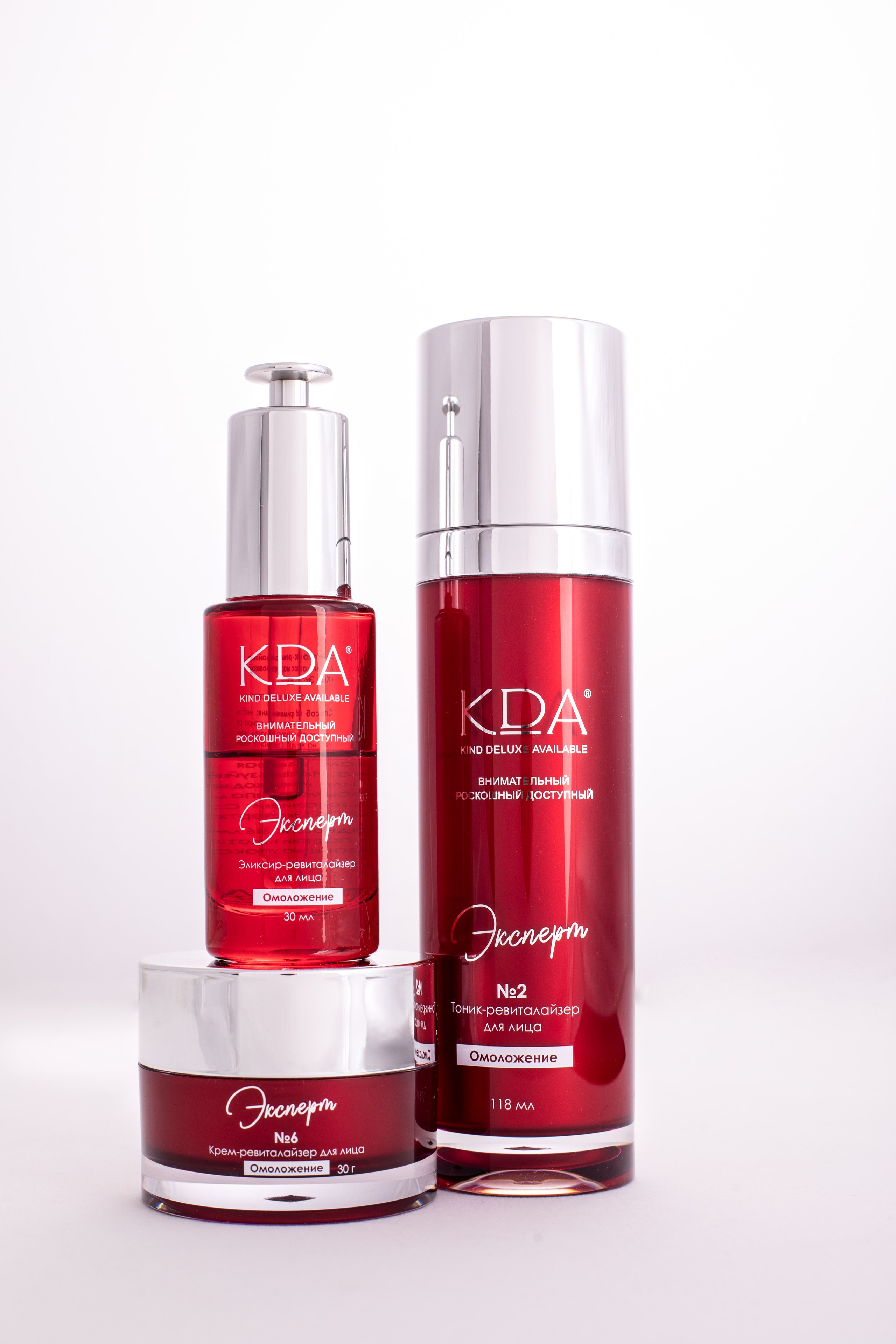 Три красных флакона косметических жидкостей на белом фоне