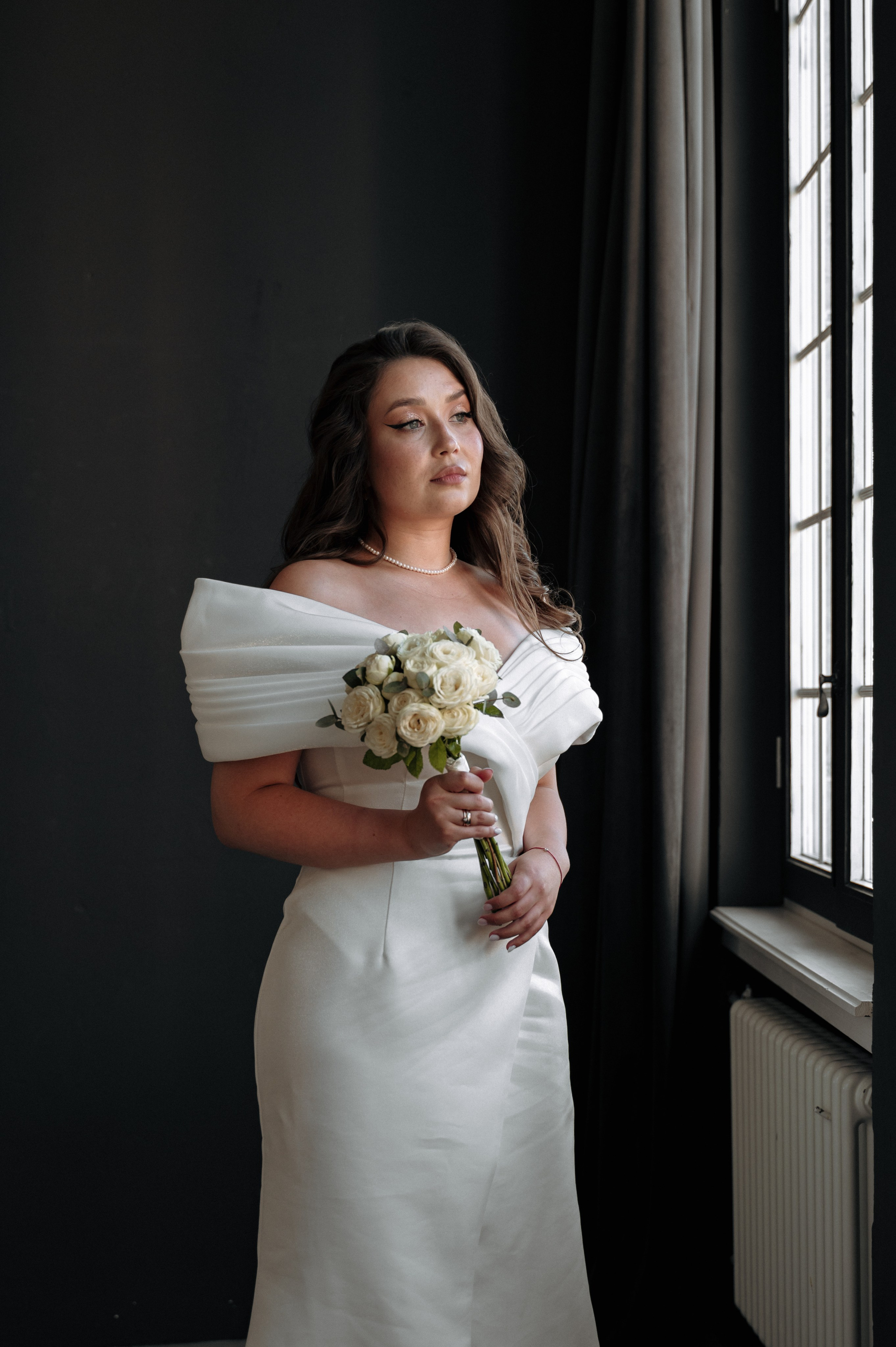 портрет невесты у окна в белом платье на черном фоне, контрастная фотография