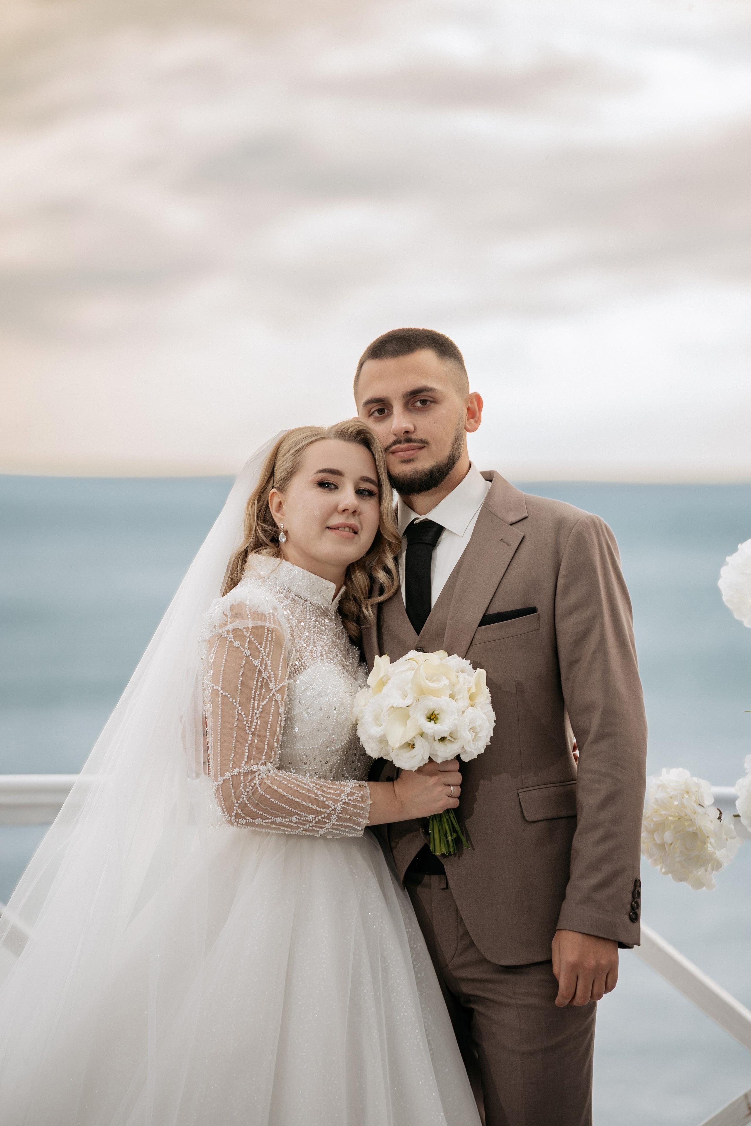 Эмоциональный портрет невесты и жениха  от фотографа на свадьбе в Геленджике с видом на море. Фотограф Геленджик - пара на террасе ресторана с видом на море во время заката.