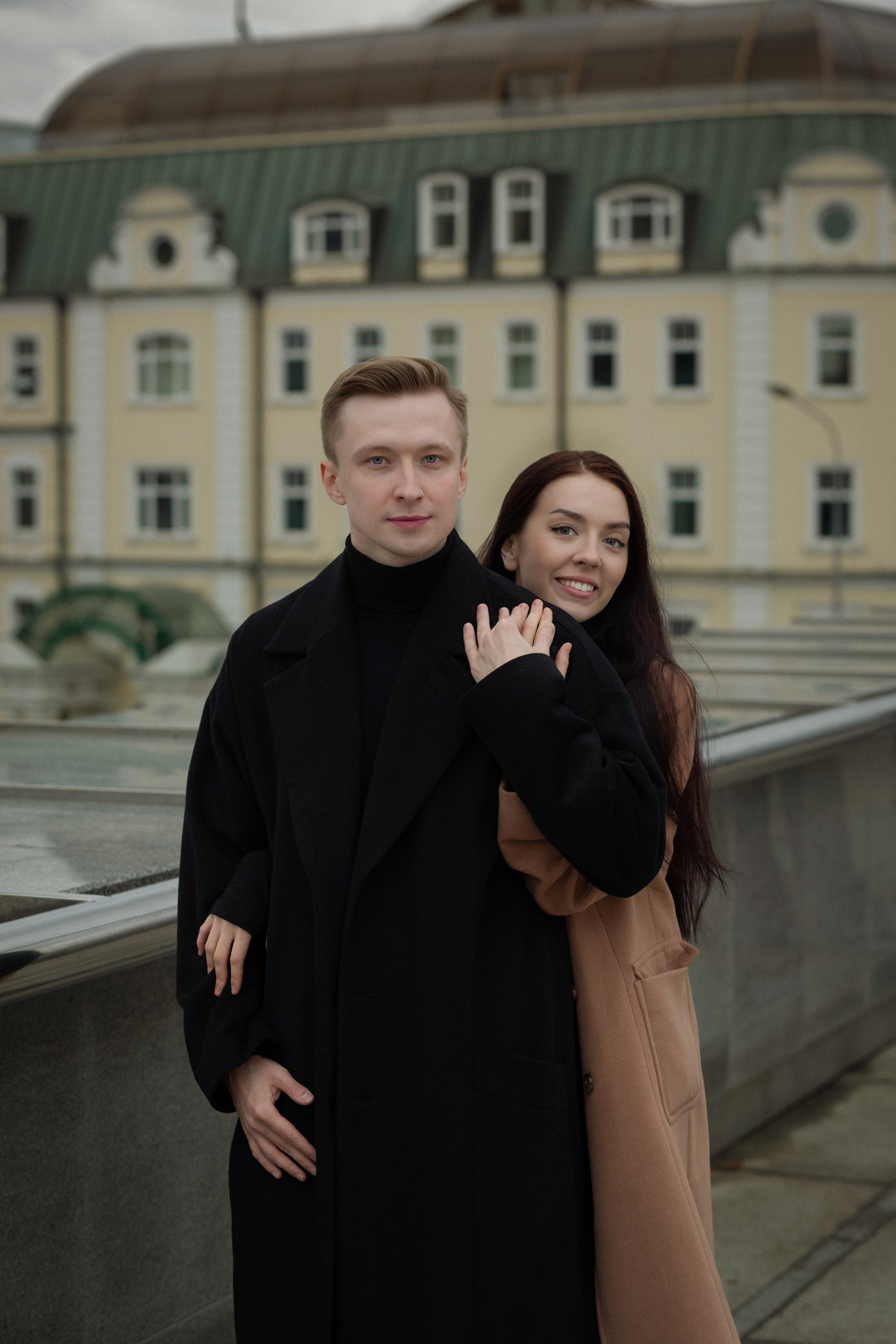 Романтичная прогулка пары — чёрные пальто и осенняя классика.