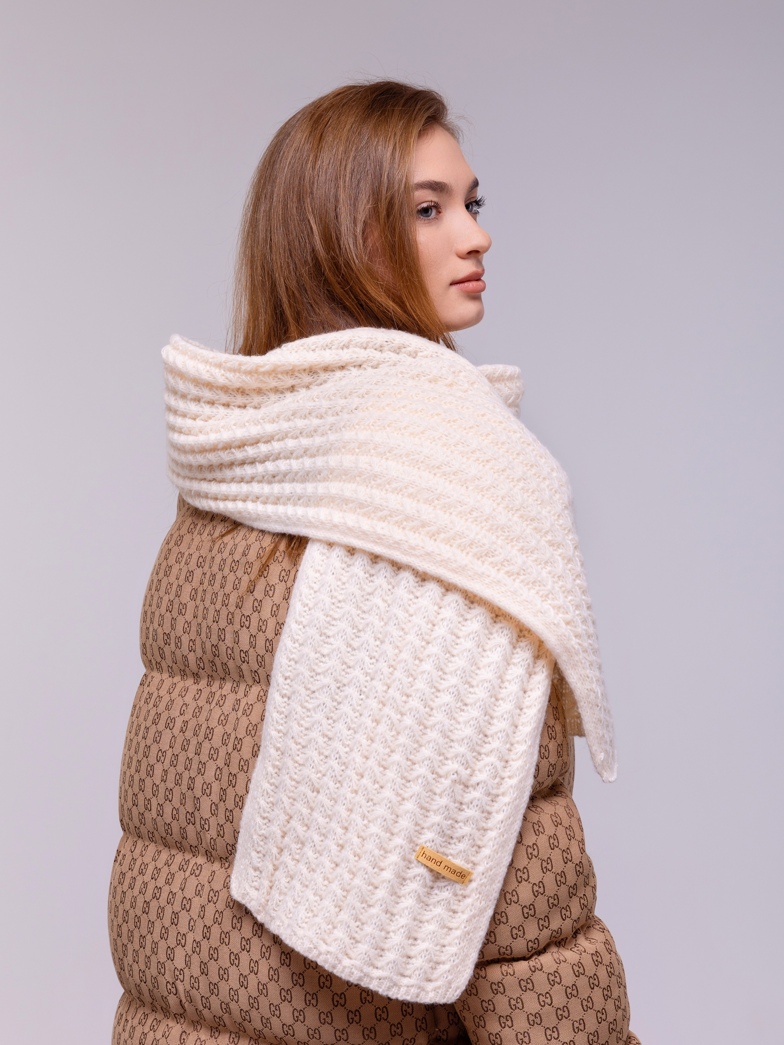 Белый шарф обвернув плечи спускается поверх куртки на грудь и спину.