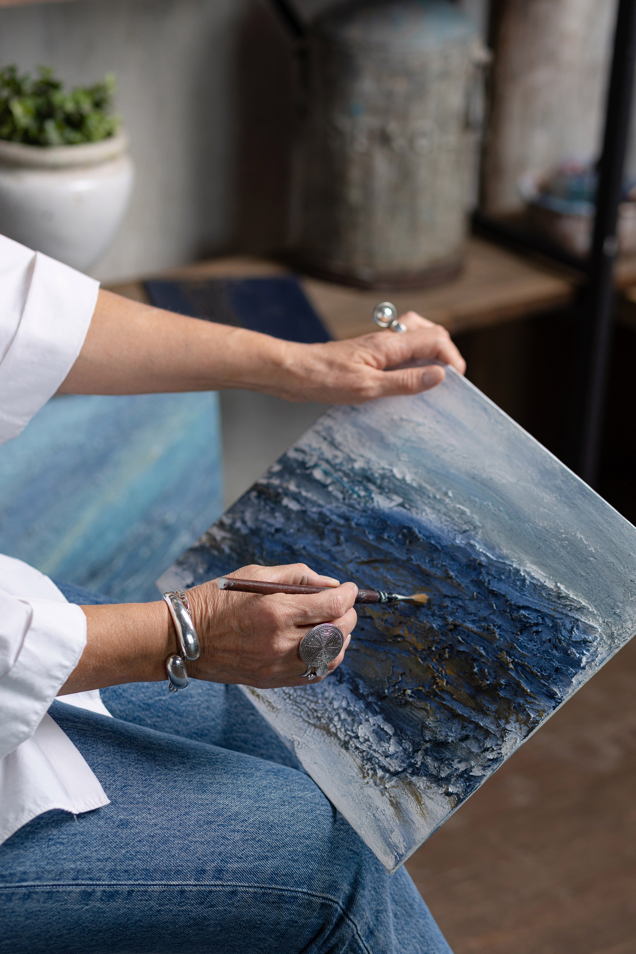 На фотографии руки художницы, пишущие картину.